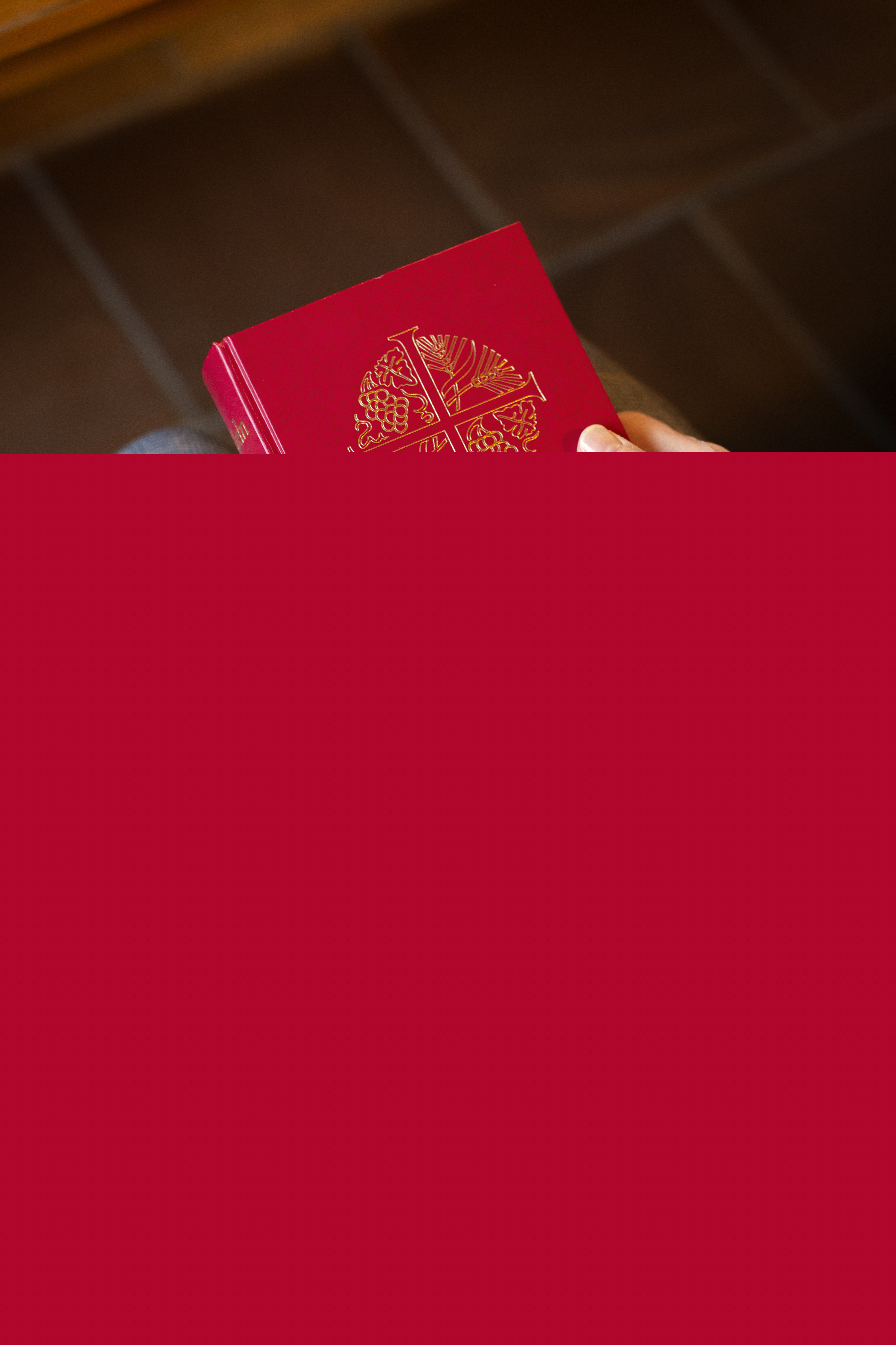 En person sitter i en kyrkbänk med en bibel i knät.