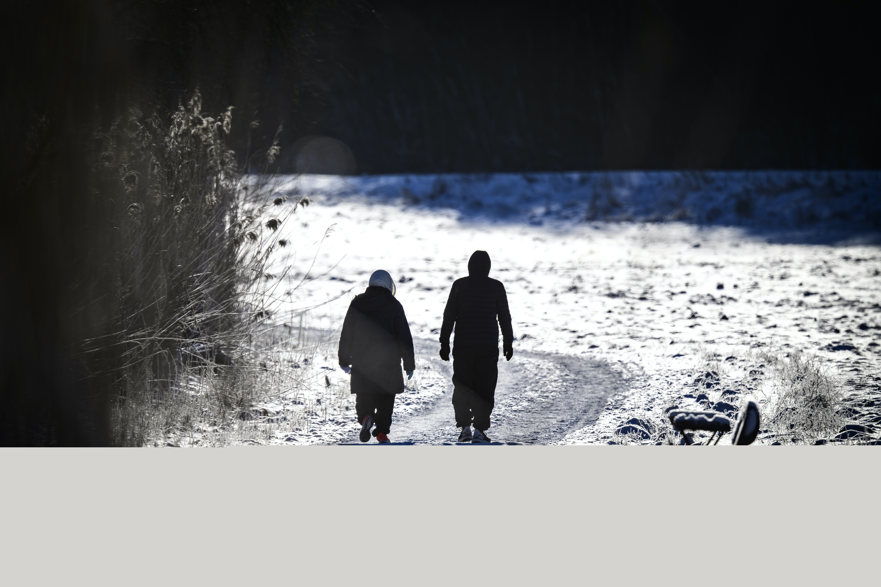 Två personer är ute på långpromenad. Det är vinter och solen skiner.