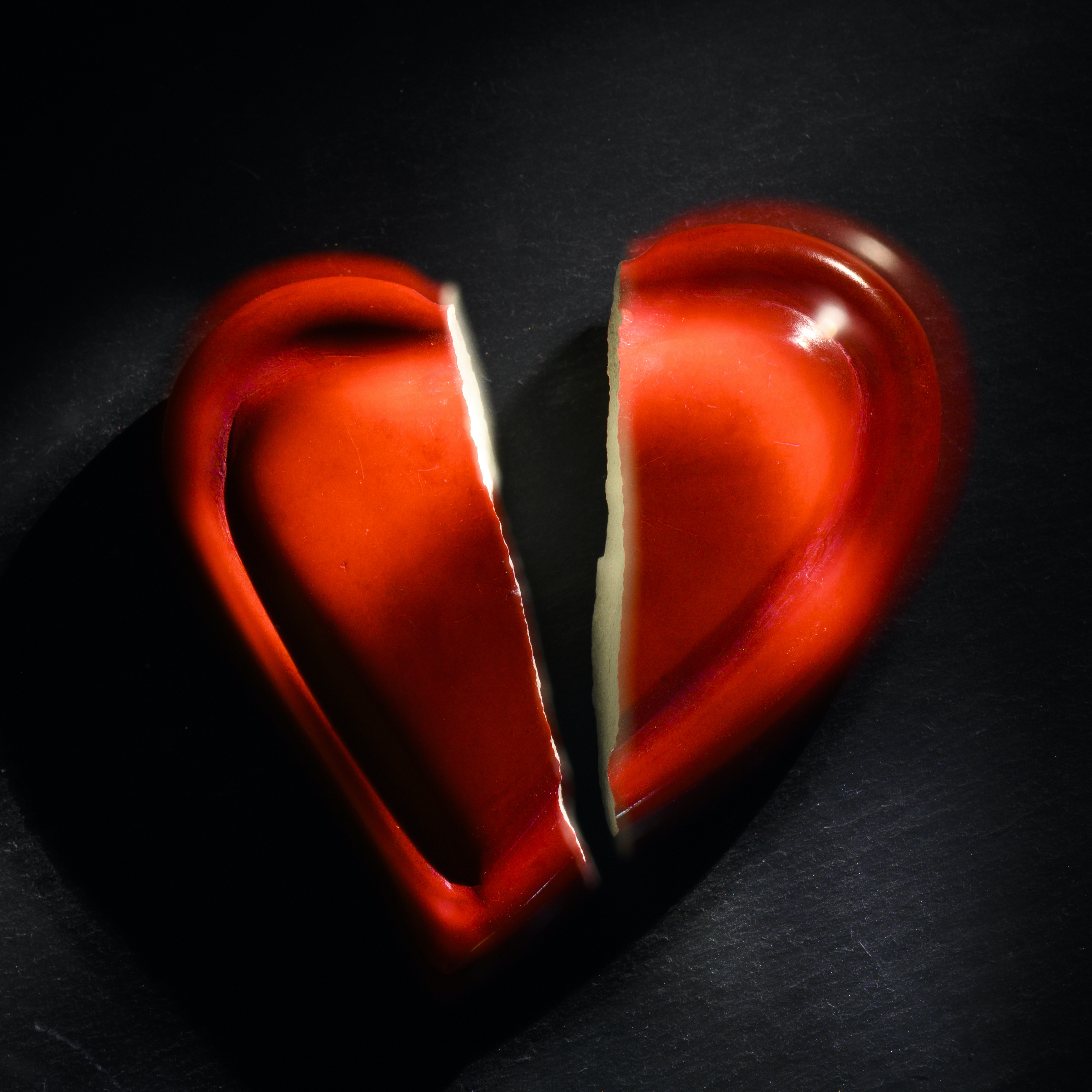 Rött keramikhjärta som spruckit mitt itu.