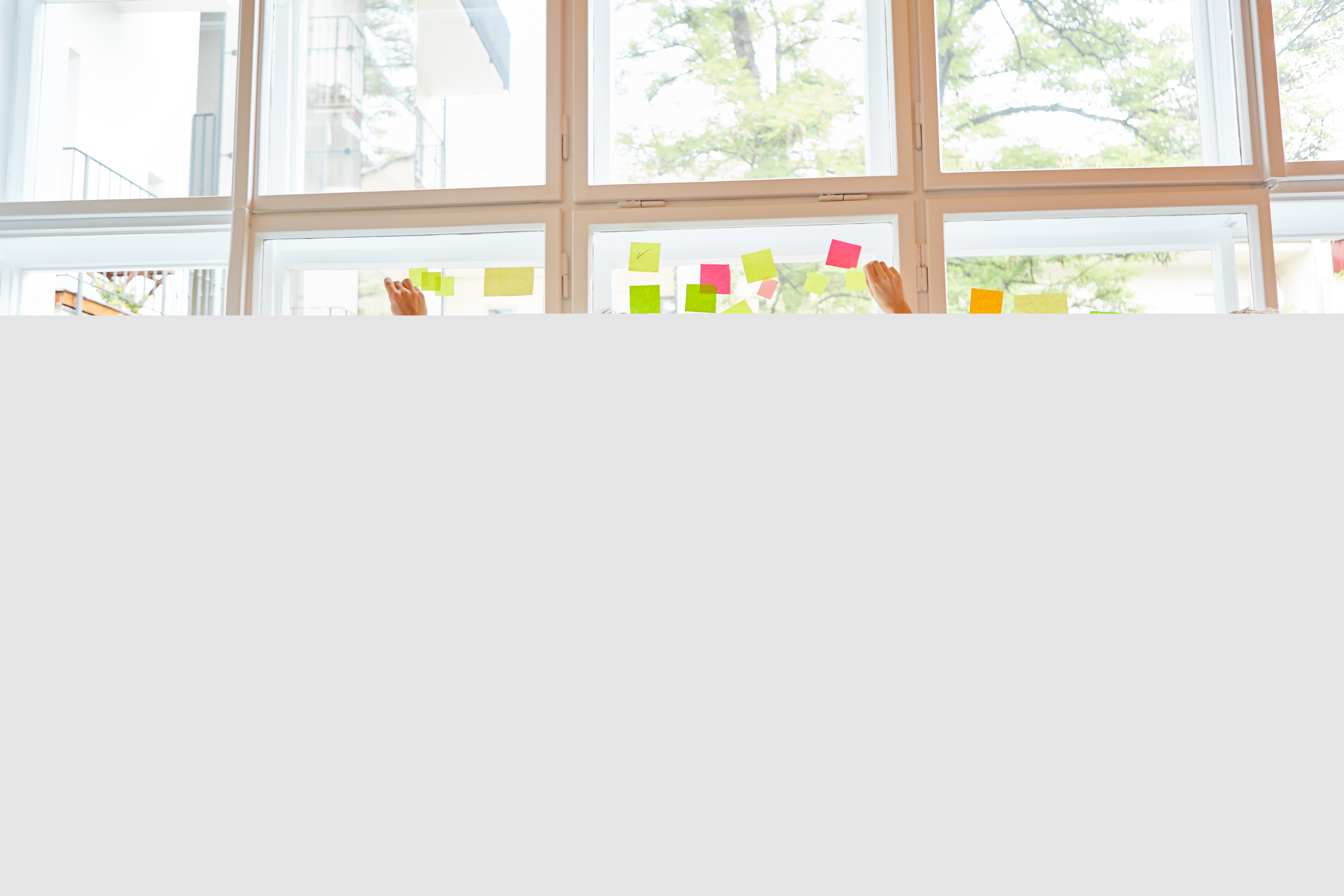 Några ungdomar sätter upp en massa olikfärgade post it-lappar på ett stort fönster.