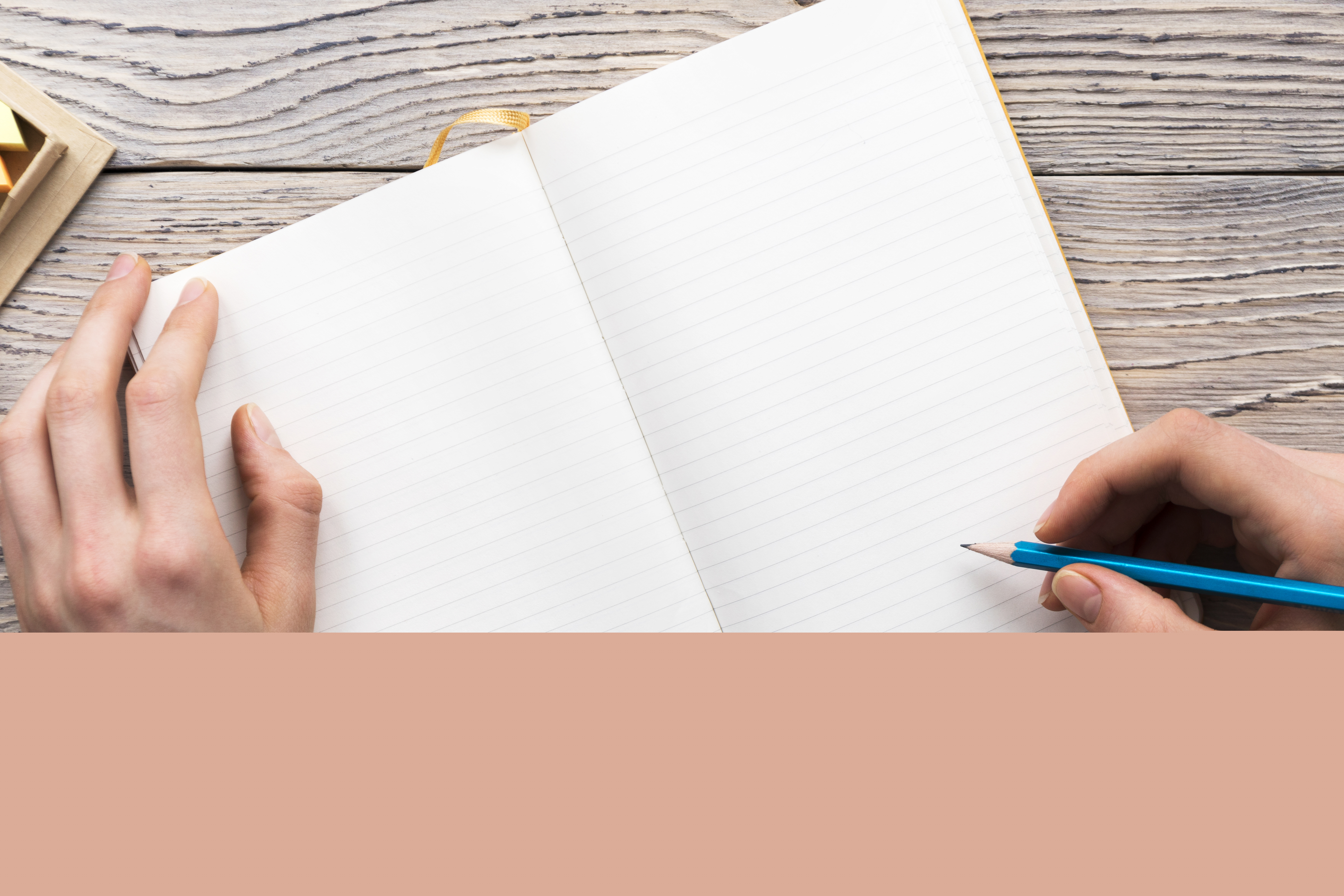 Någon skriver i ett tomt anteckningsblock med en blå penna.