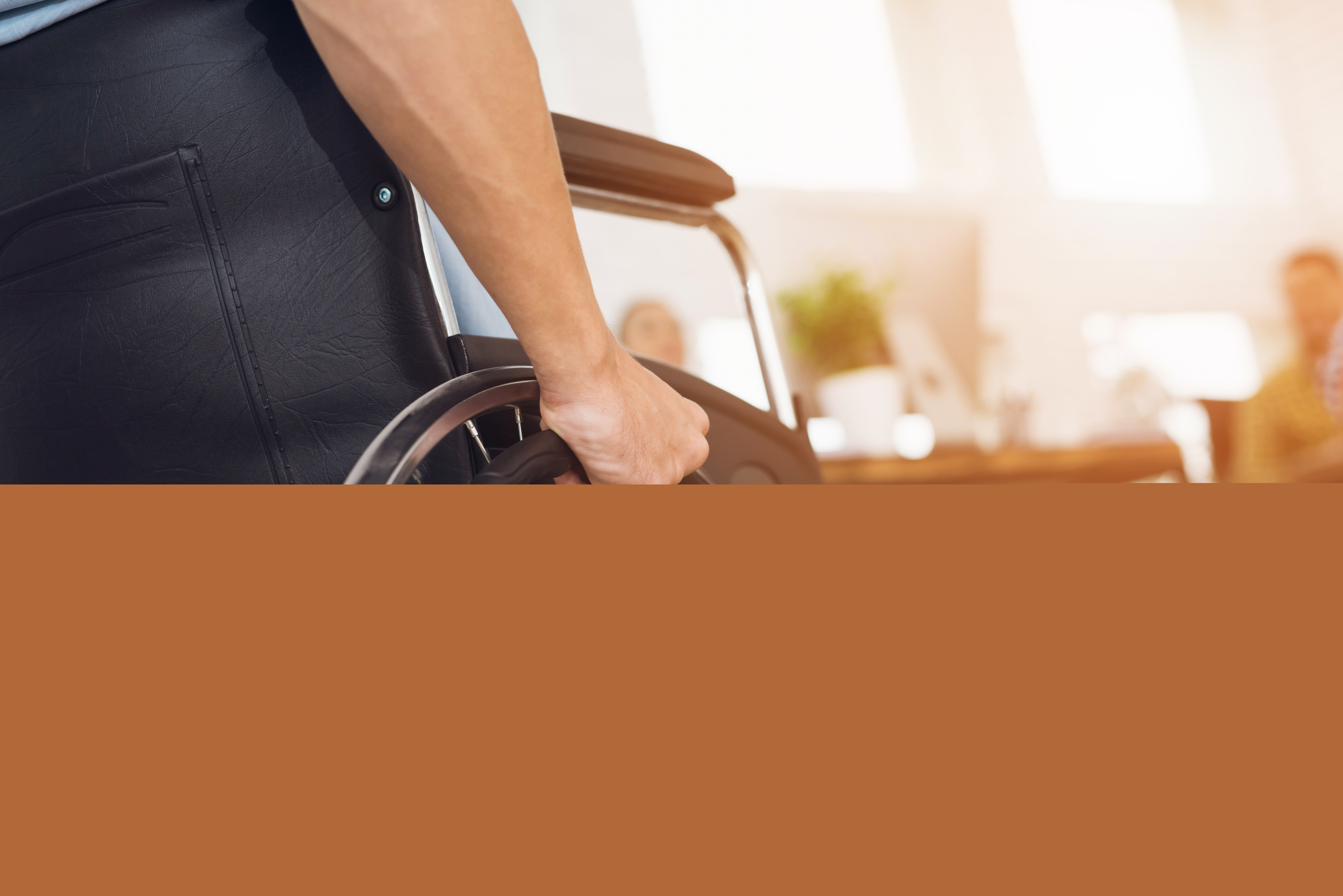 En person i rullstol håller handen runt hjulet.