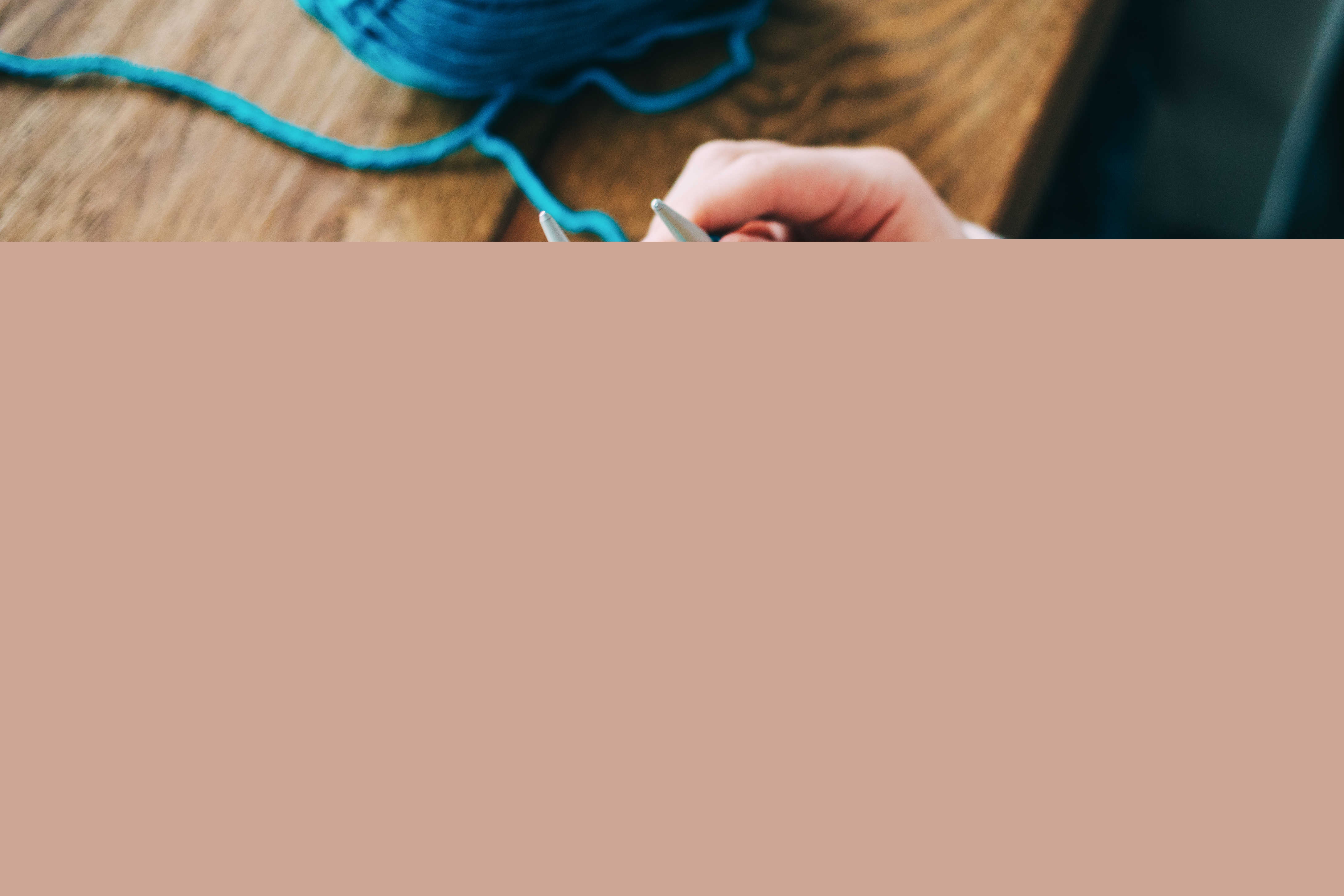 Närbild på en person som stickar med gult och blått garn.