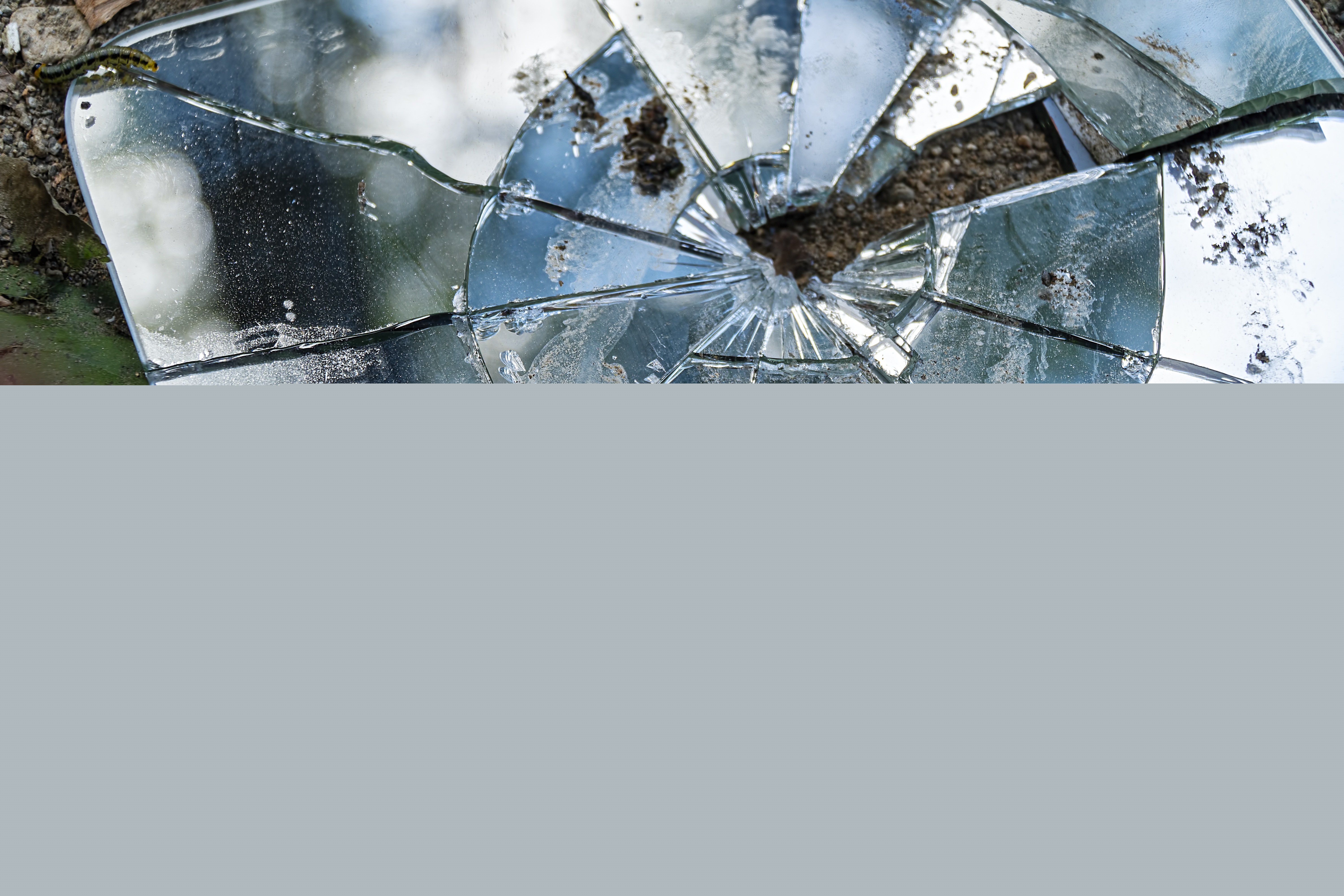 En trasig väggspegel ligger på marken.