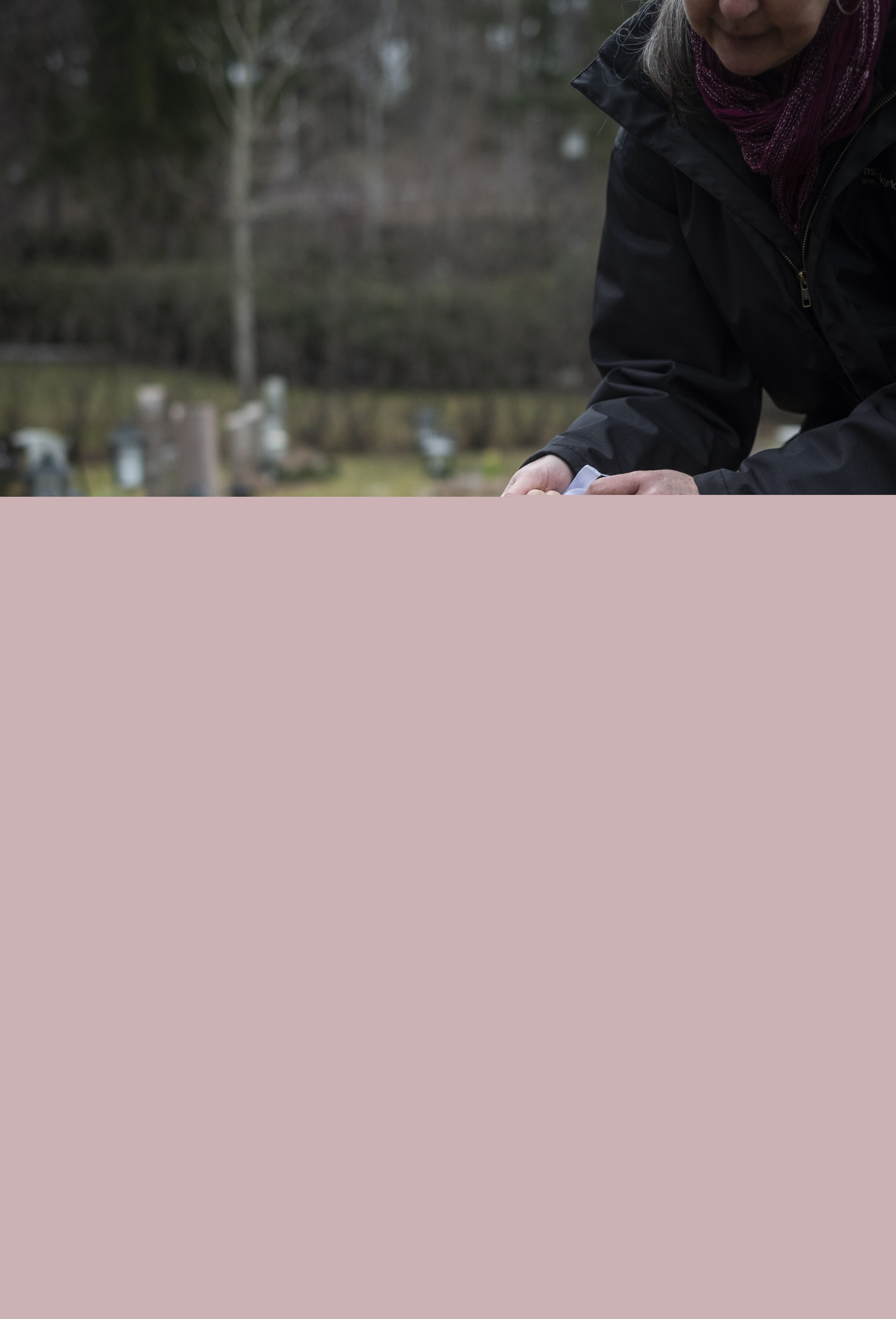 Någon sänker ner en vit urna i marken på en gravplats.