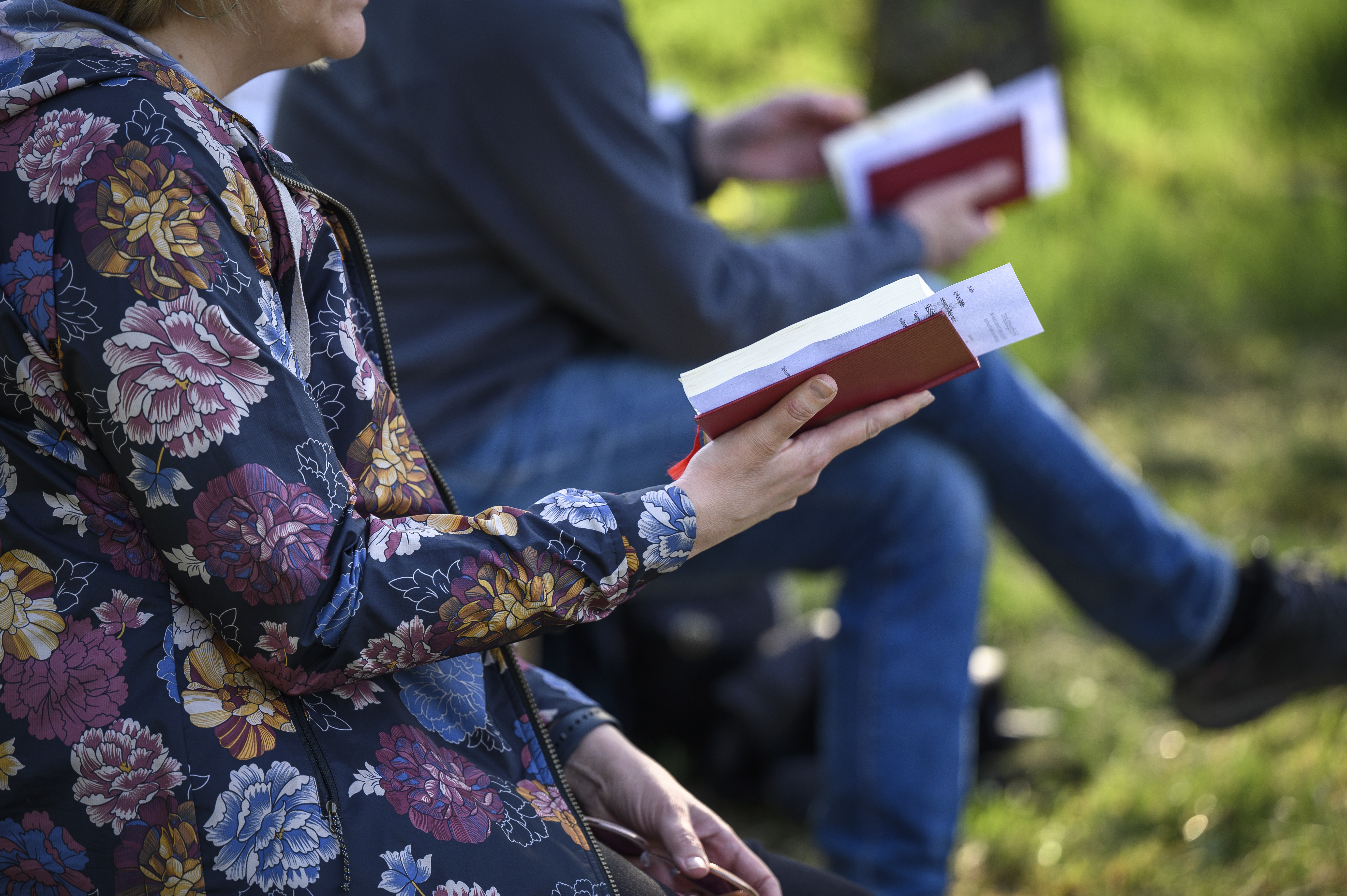 Två personer sitter bredvid varandra utomhus med varsin psalmbok.