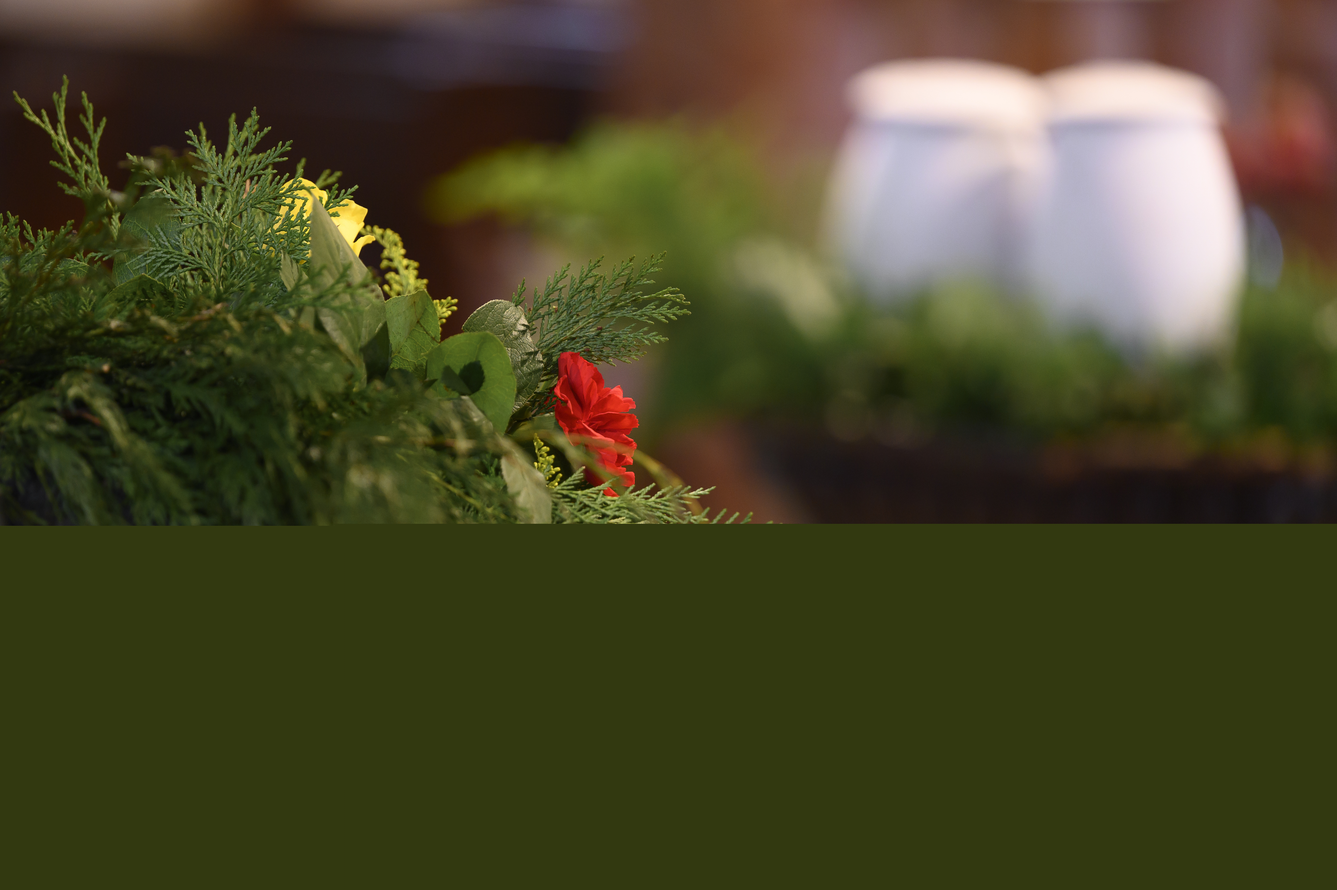 Ett blomsterarrangemang i förgrunden. Längre bort syns två urnor.