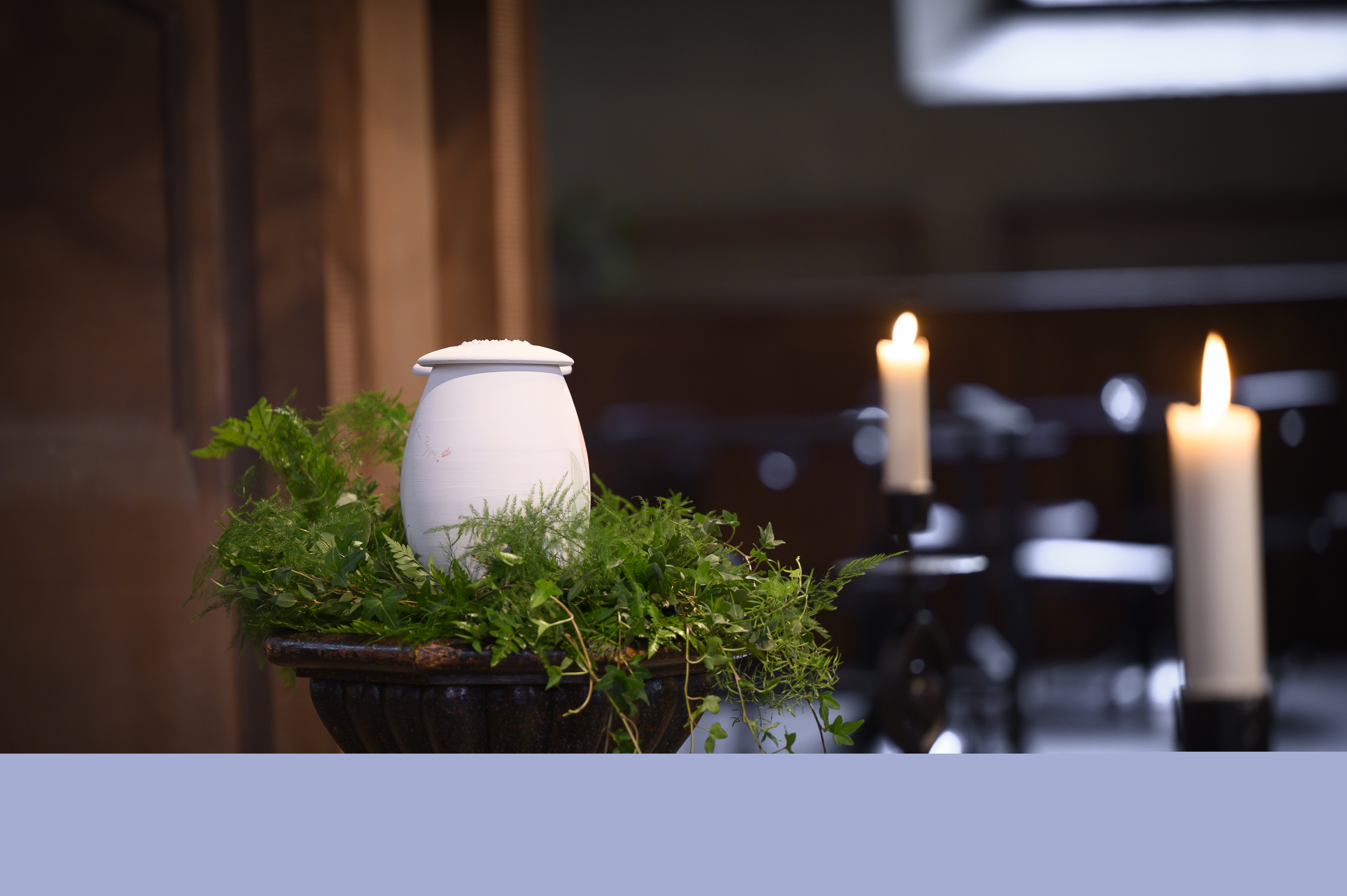 En urna står uppställd bland ormbunksblad i kyrkan.