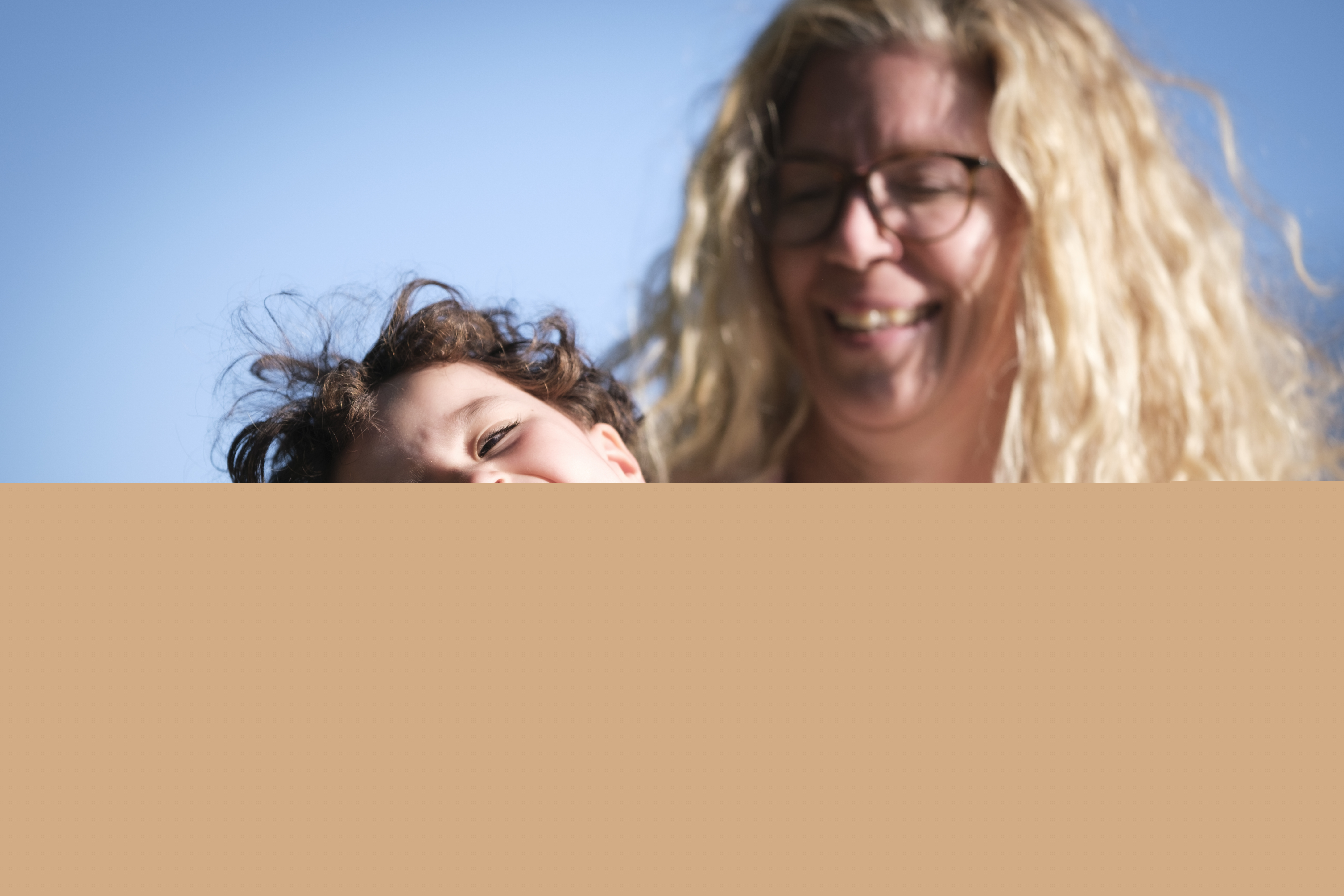 Ett barn gapskrattar i sin mammas knä.