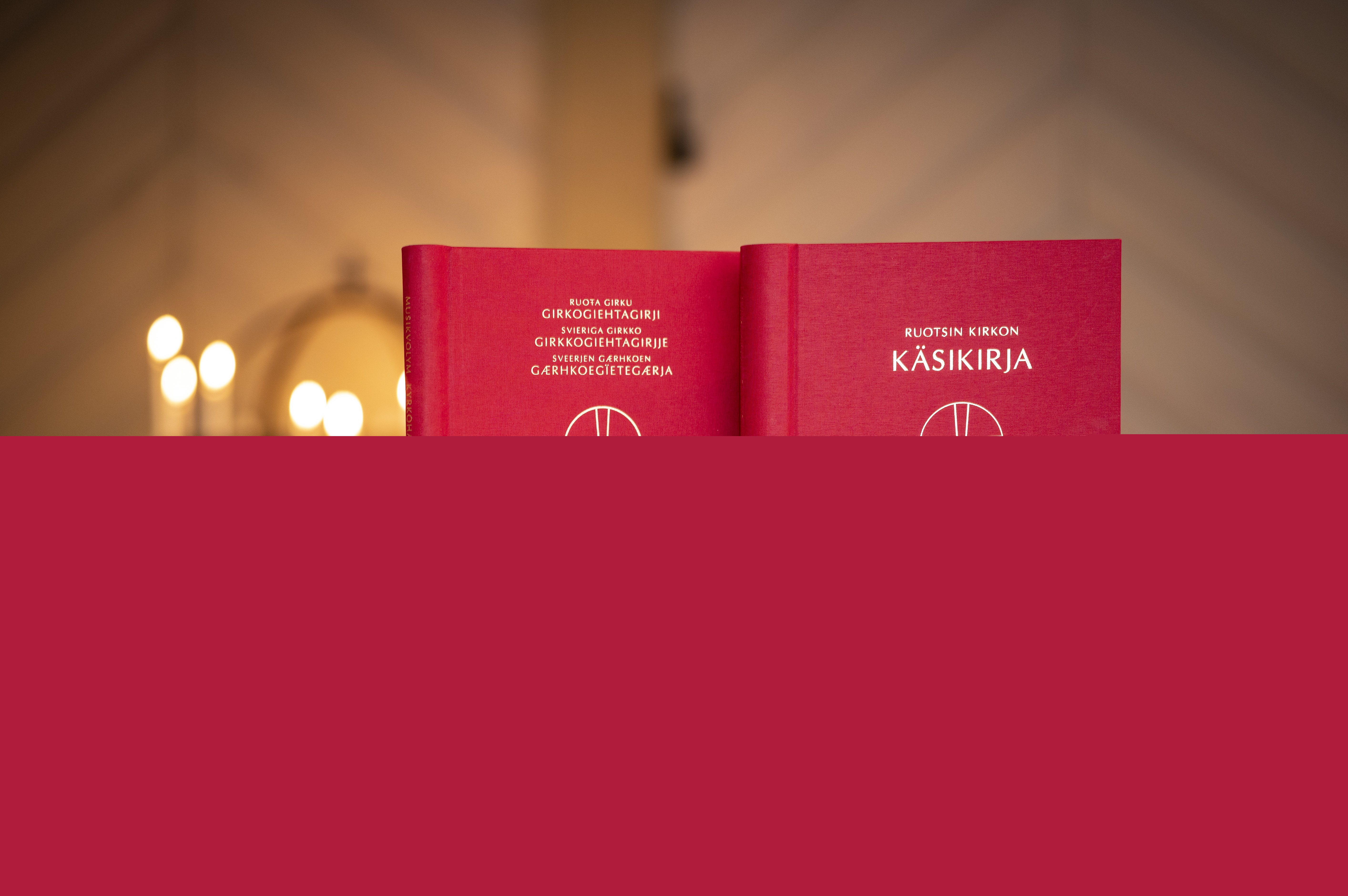 Två kyrkliga publikationer på minoritetsspråk står uppställda på ett bord i en kyrka.