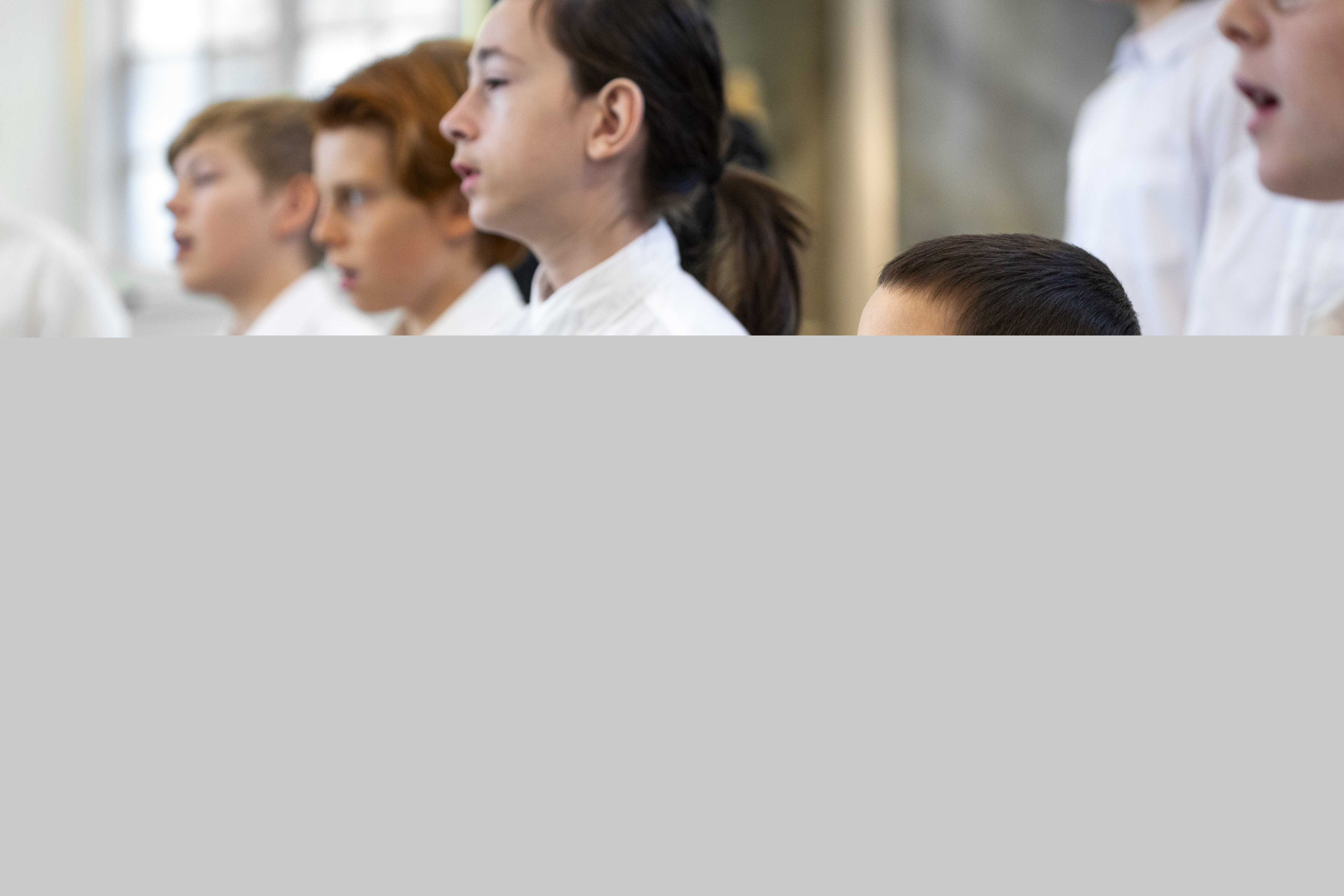 Närbild på medlemmar i en barnkör som sjunger i en kyrka.