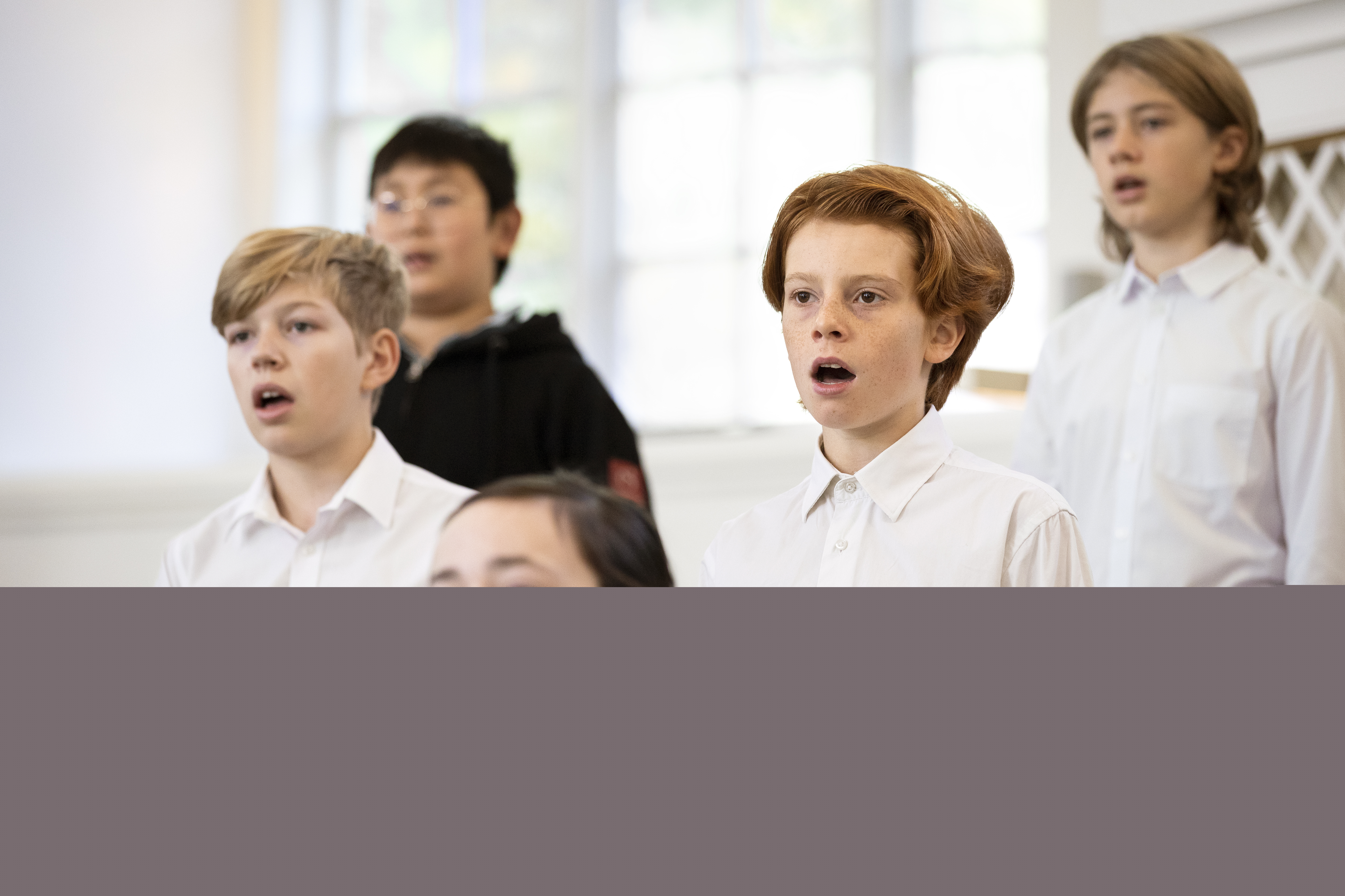 Närbild på medlemmar i en barnkör som sjunger i en kyrka.