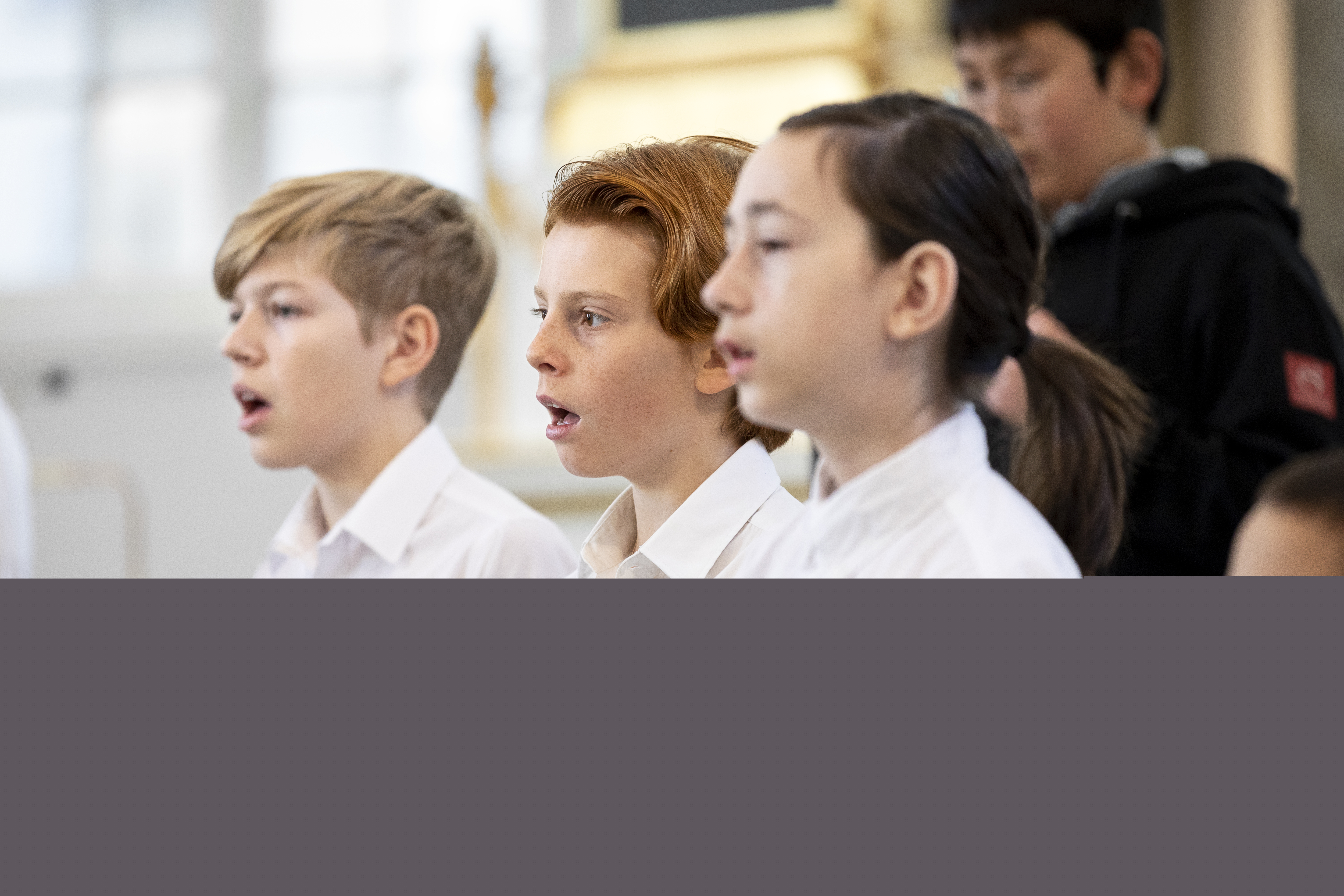 Närbild på medlemmar i en barnkör som sjunger i en kyrka.