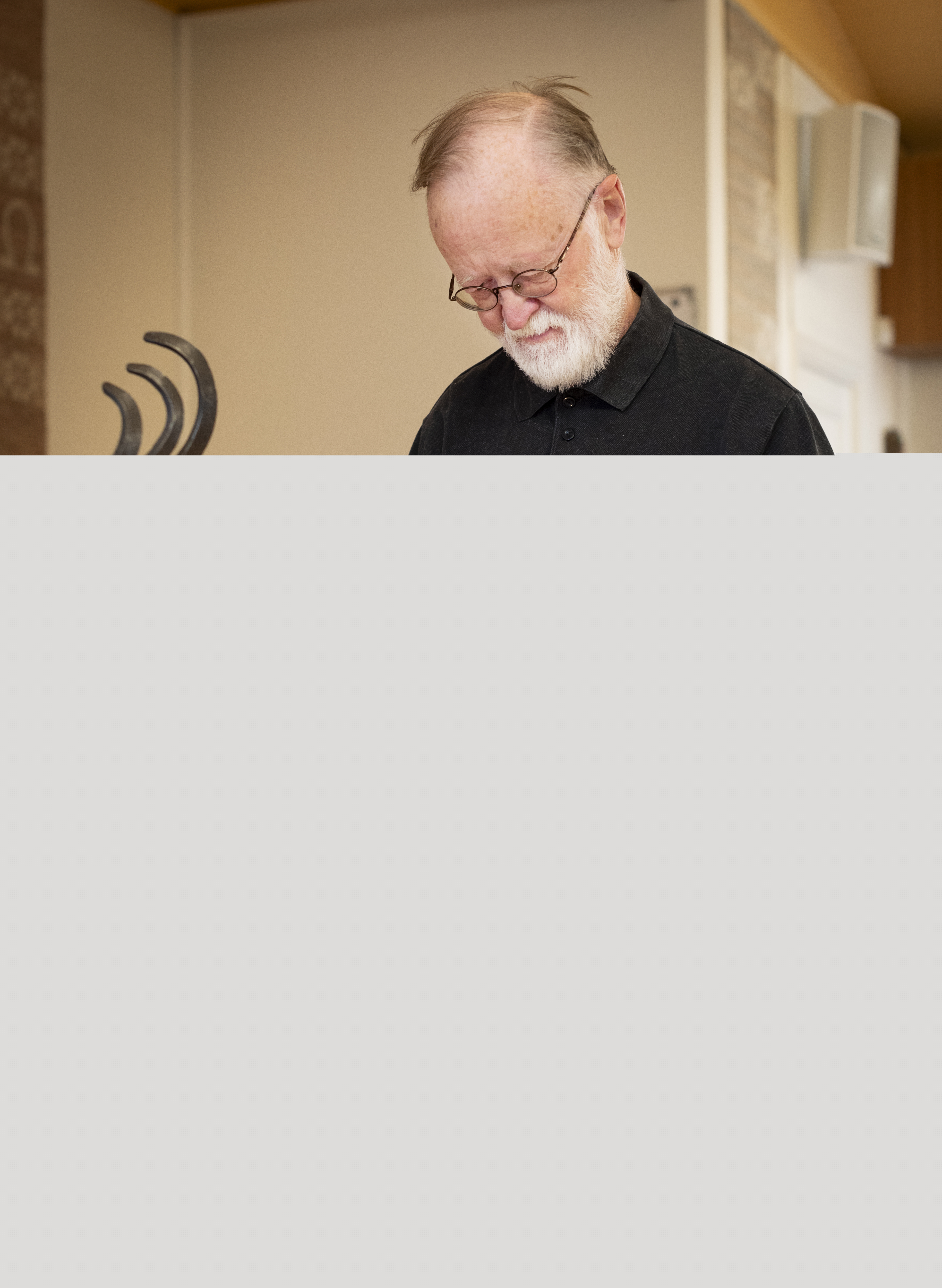 En svartklädd man sätter ett tänt ljus i en svart 
smidesljusstake.