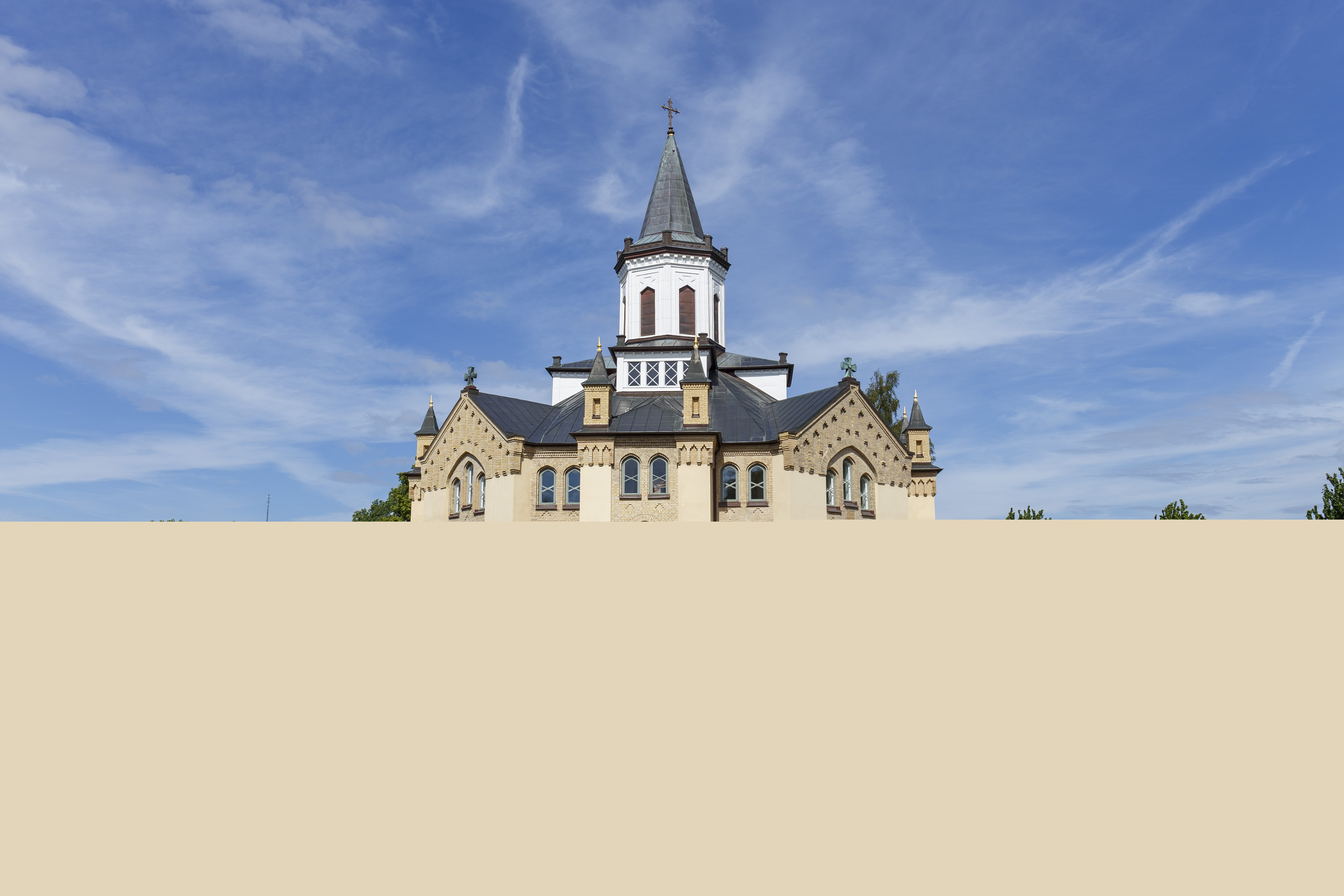 En åttkantig kyrka och en kyrkogård i solen.