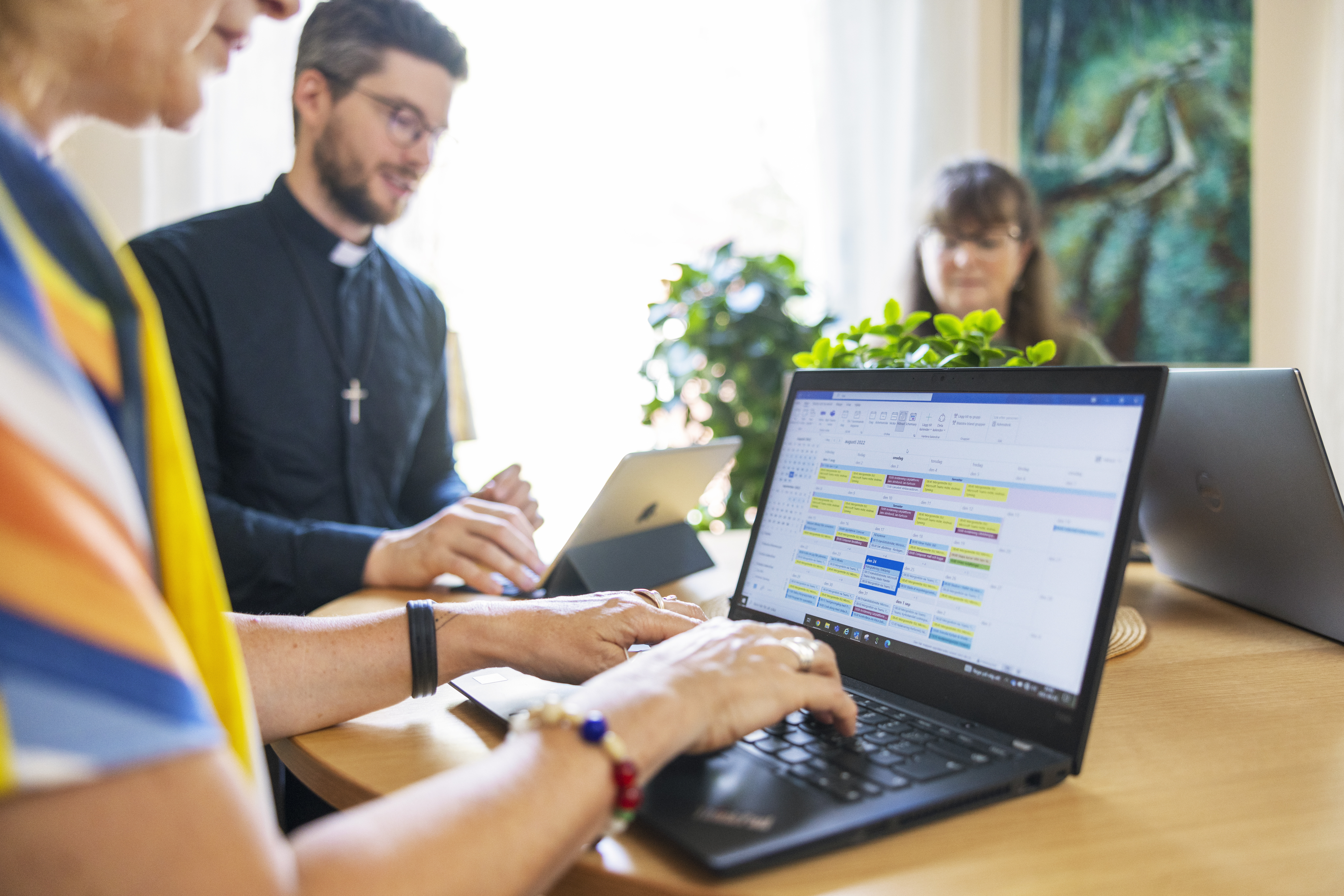 Några personer sitter runt ett bord med laptops och surfplattor och samtalar.