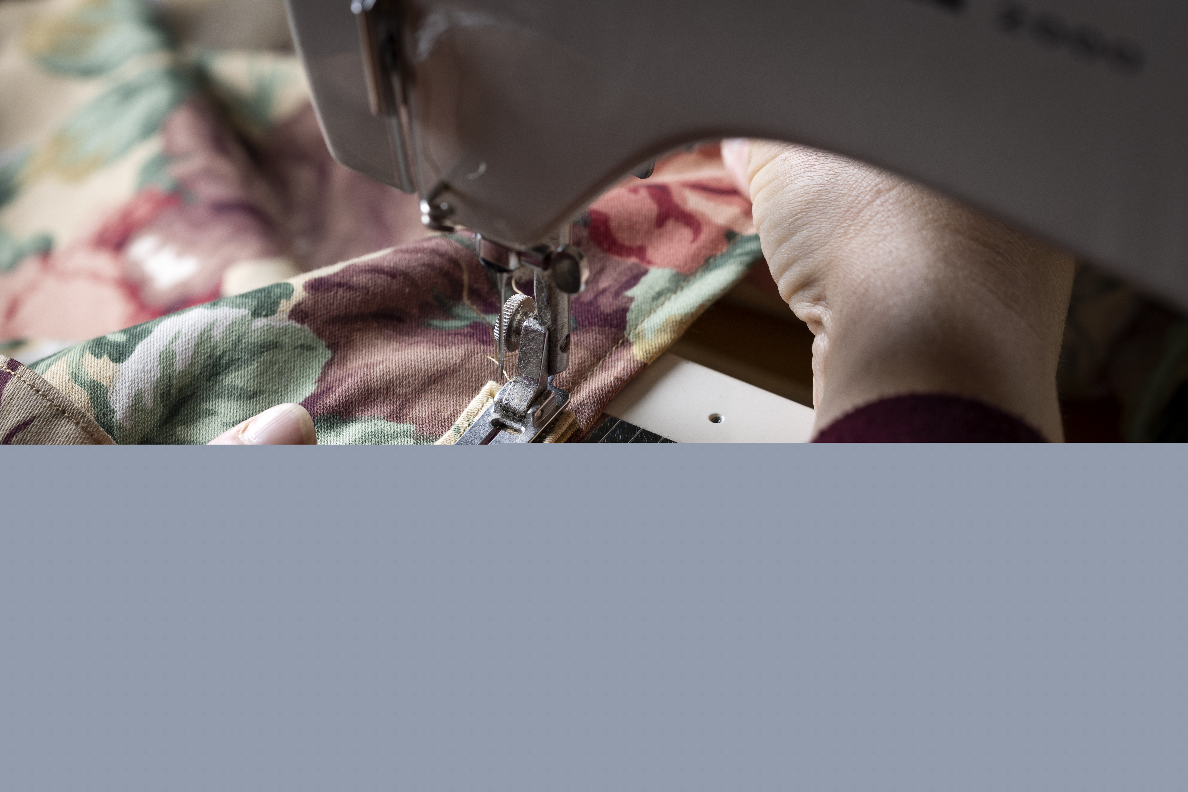 Närbild på någon som syr på en symaskin.