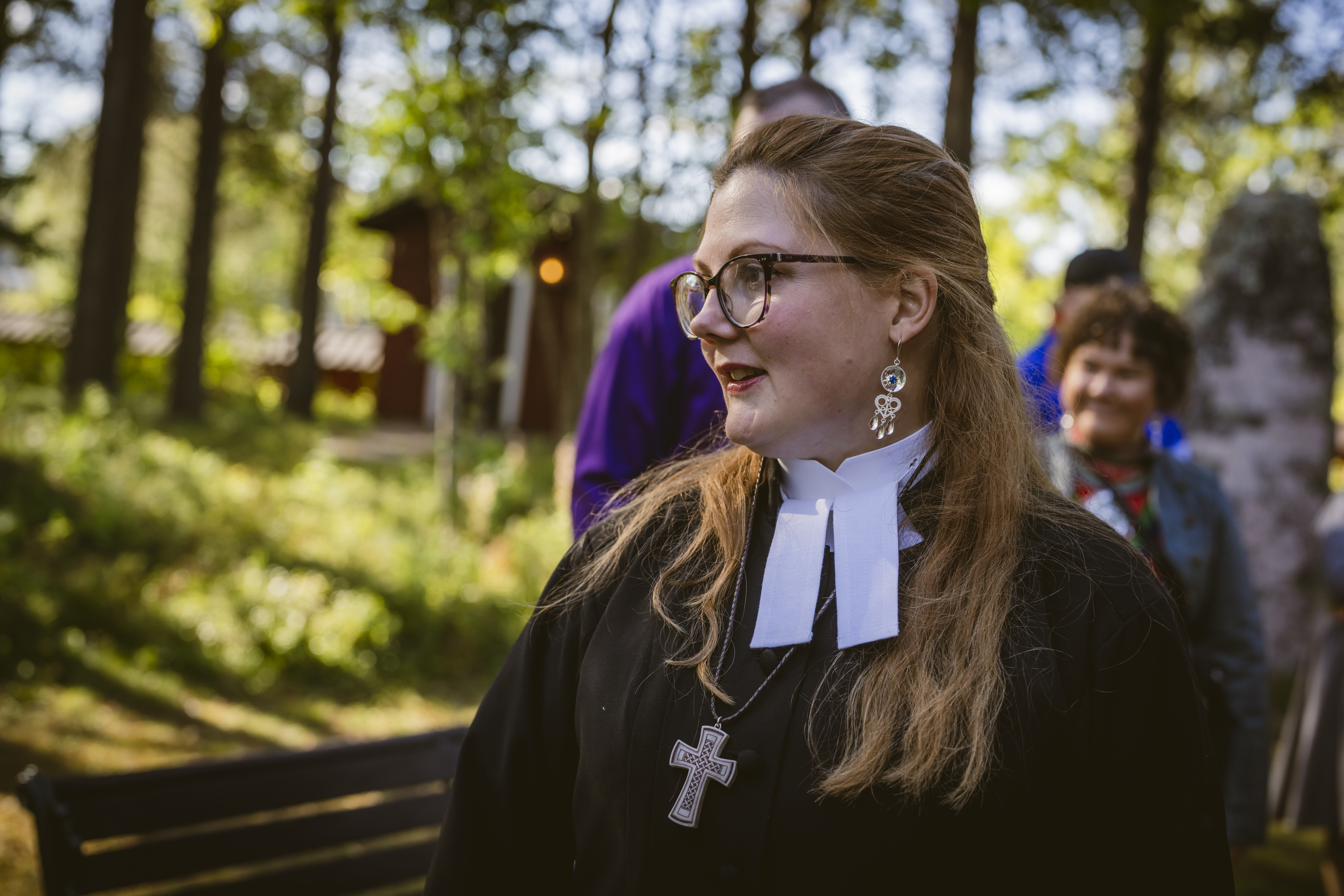 En kvinnlig präst står utomhus.