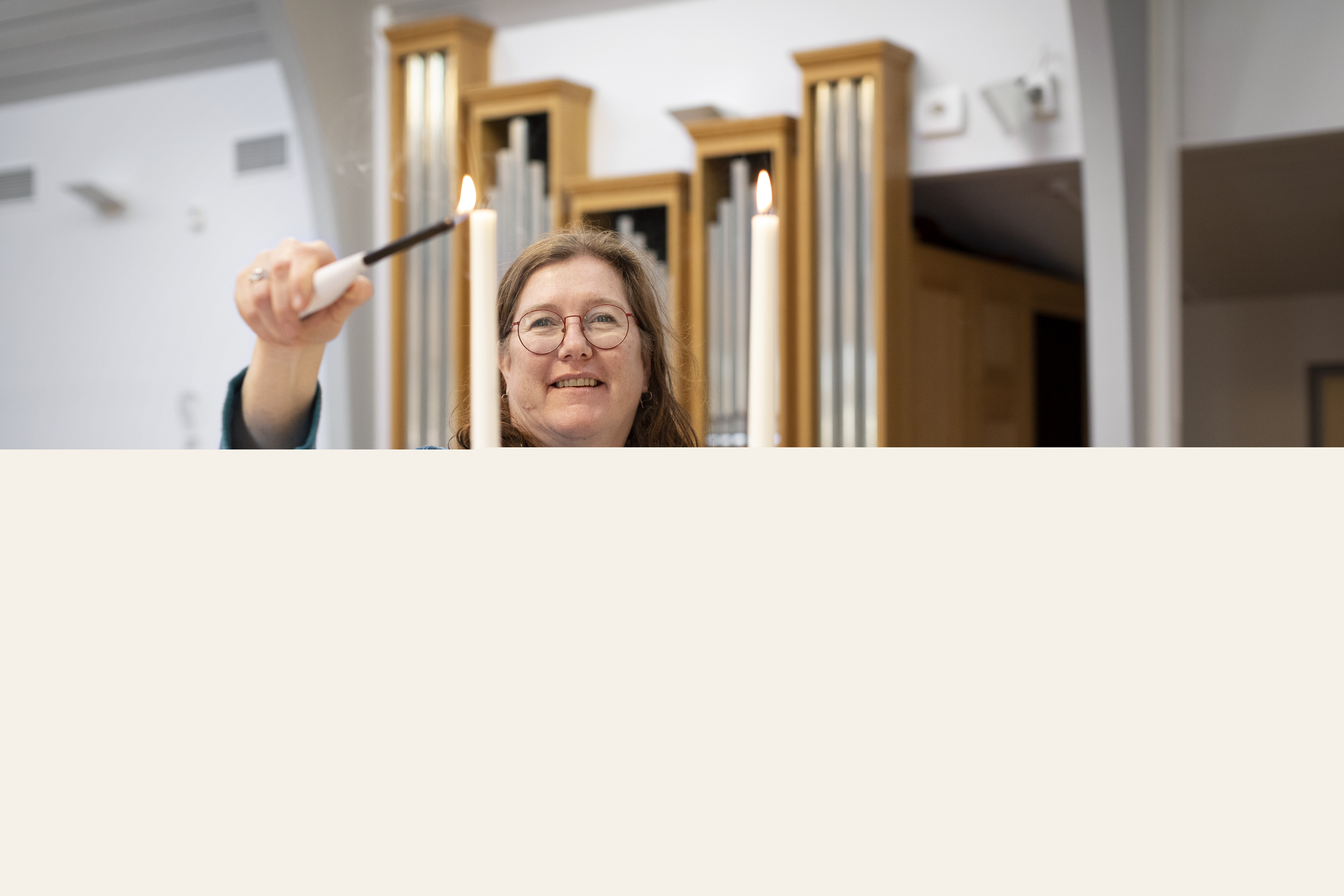 En kvinnlig diakon tänder två ljus på altaret.
