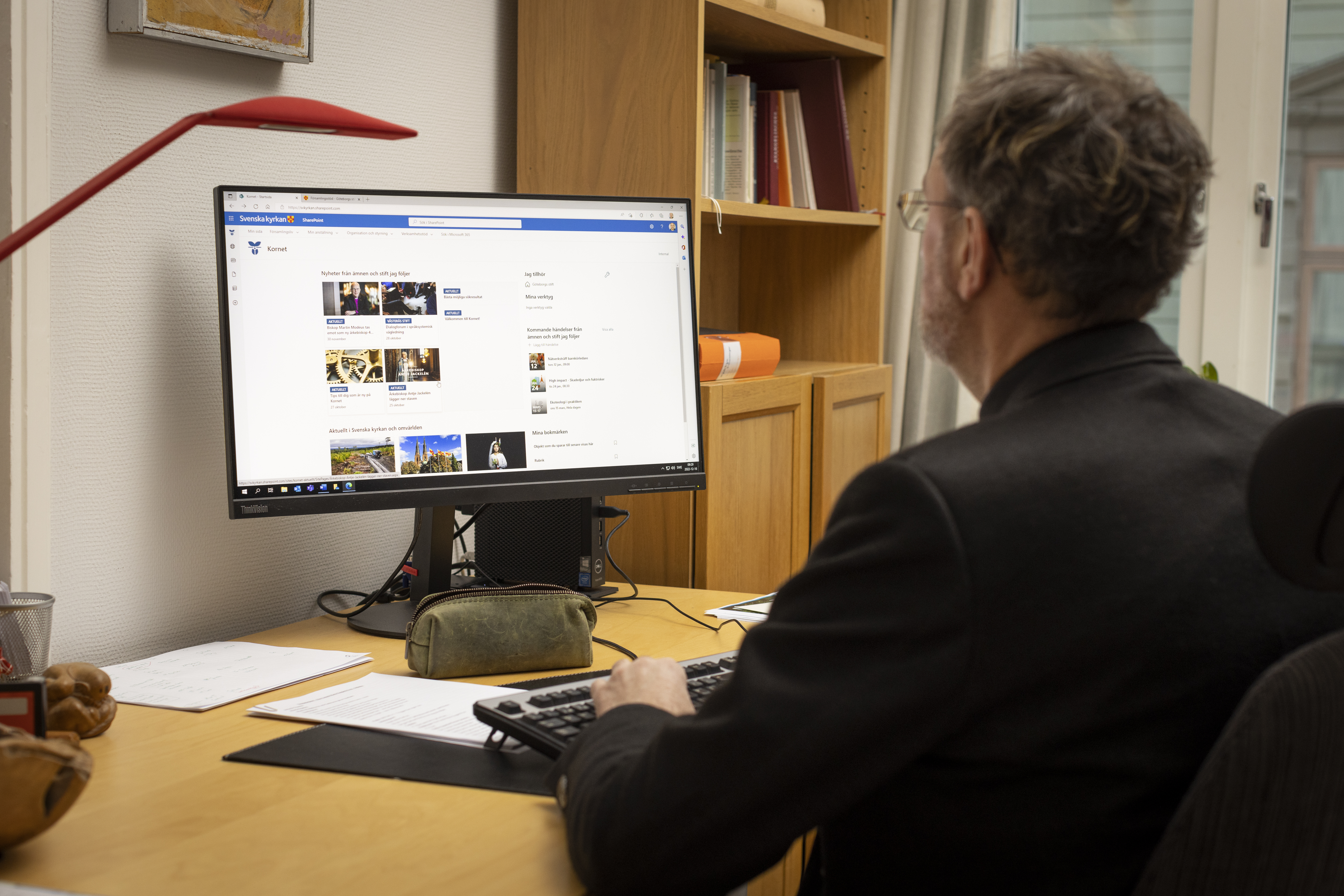 En man sitter vid ett skrivbord och arbetar i datorn.