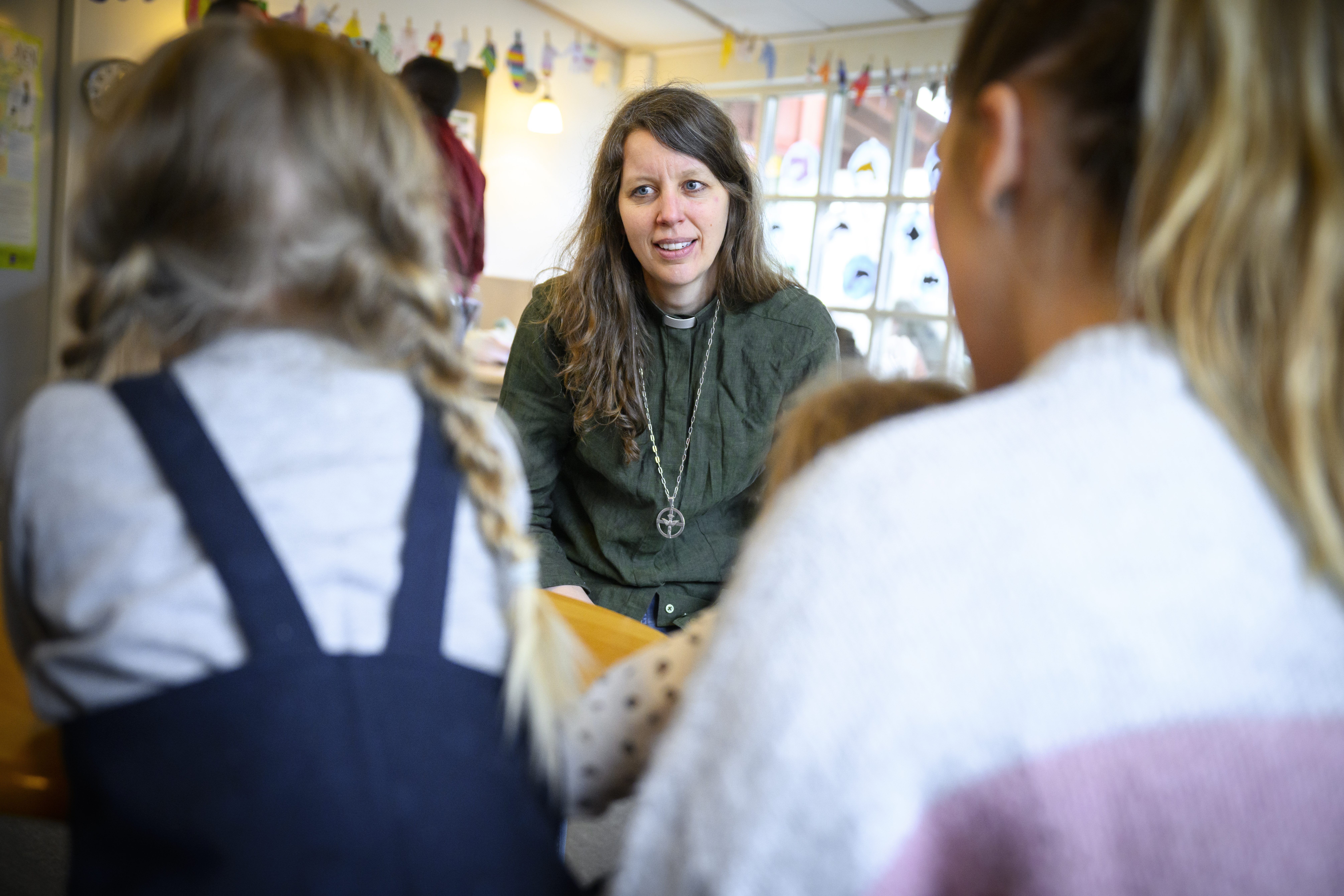 En diakon sitter och samtalar med en kvinna och två småbarn.