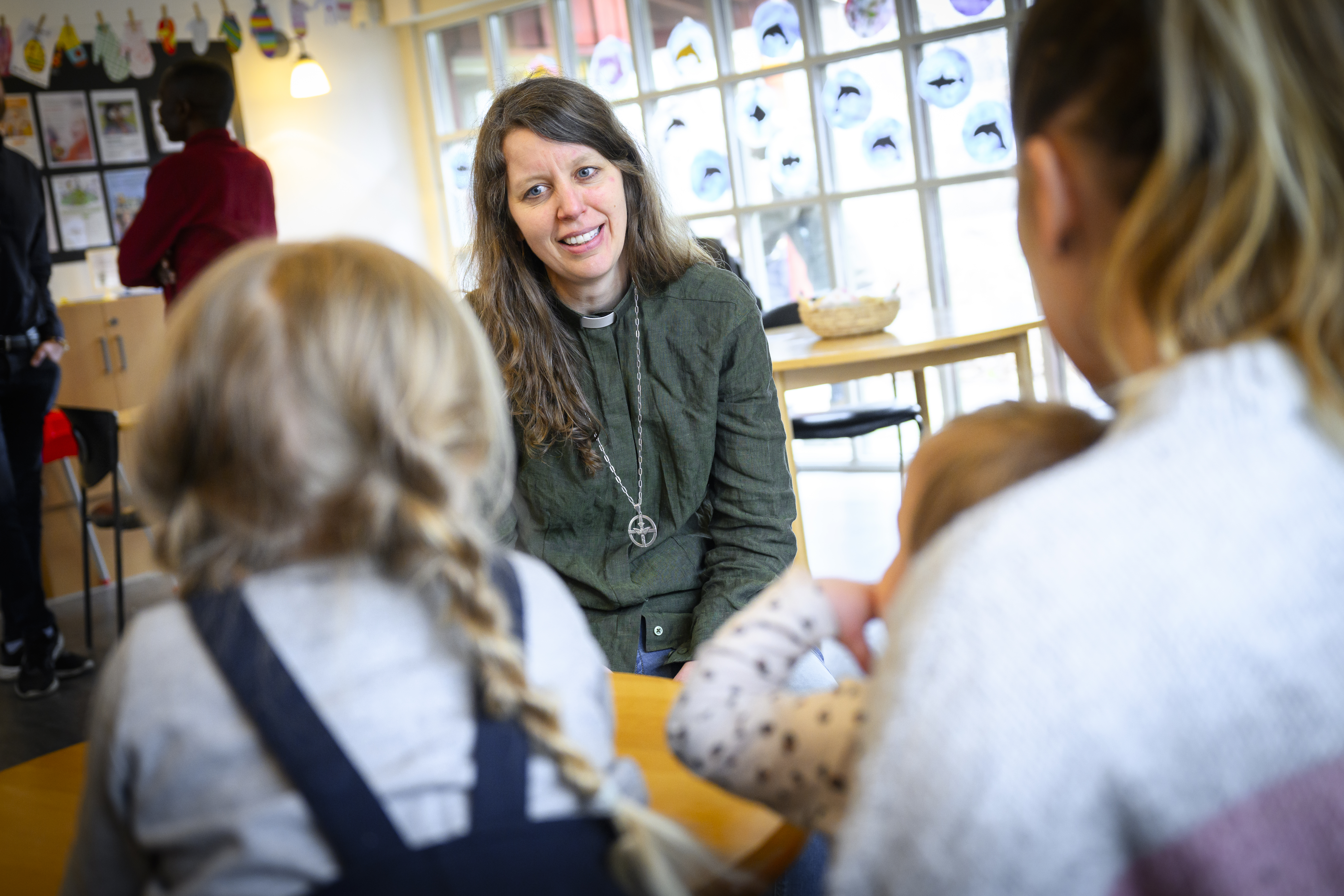 En diakon sitter och samtalar med en kvinna och två småbarn.