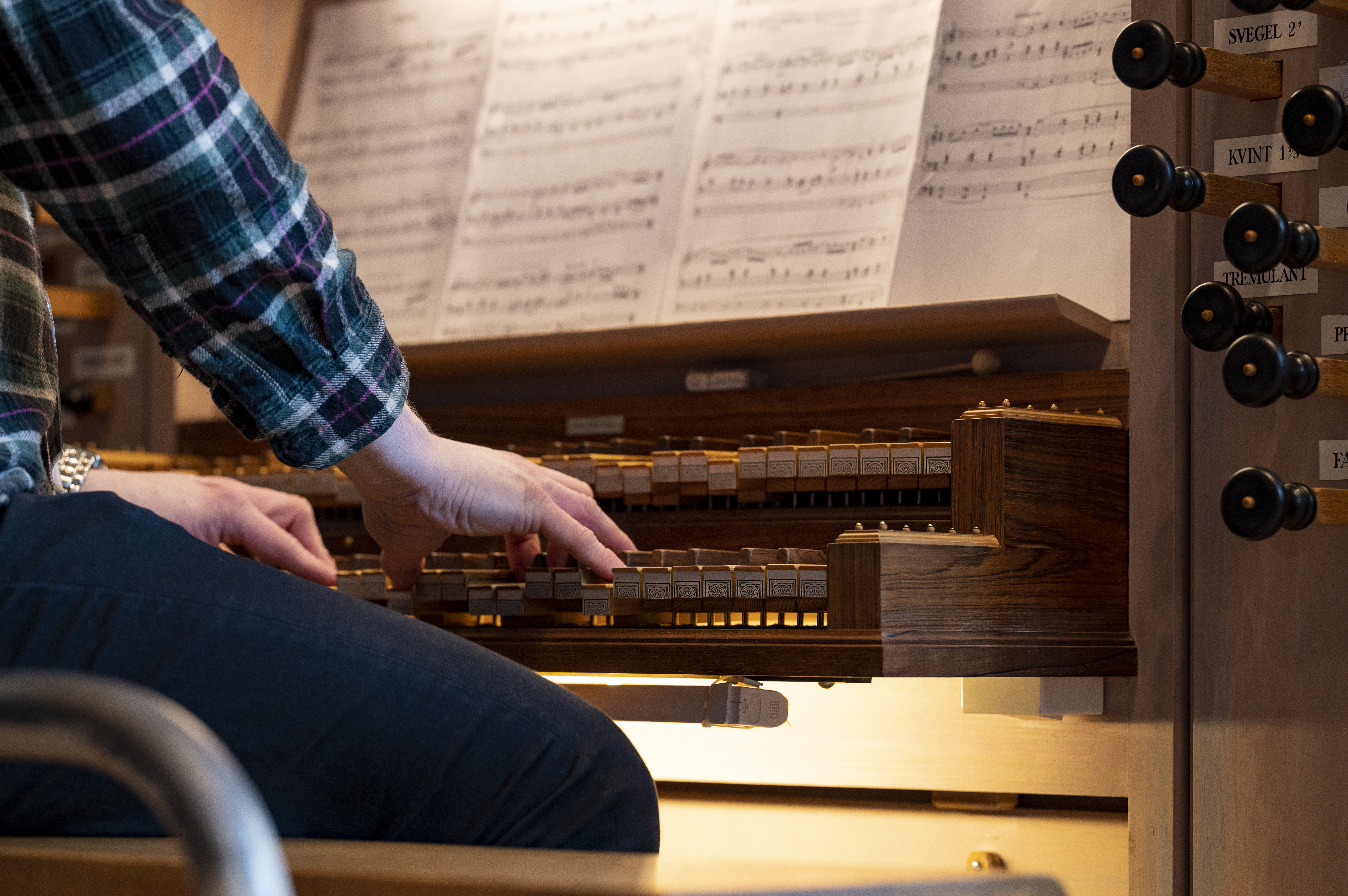 En person i rutig skjorta spelar kyrkorgel.