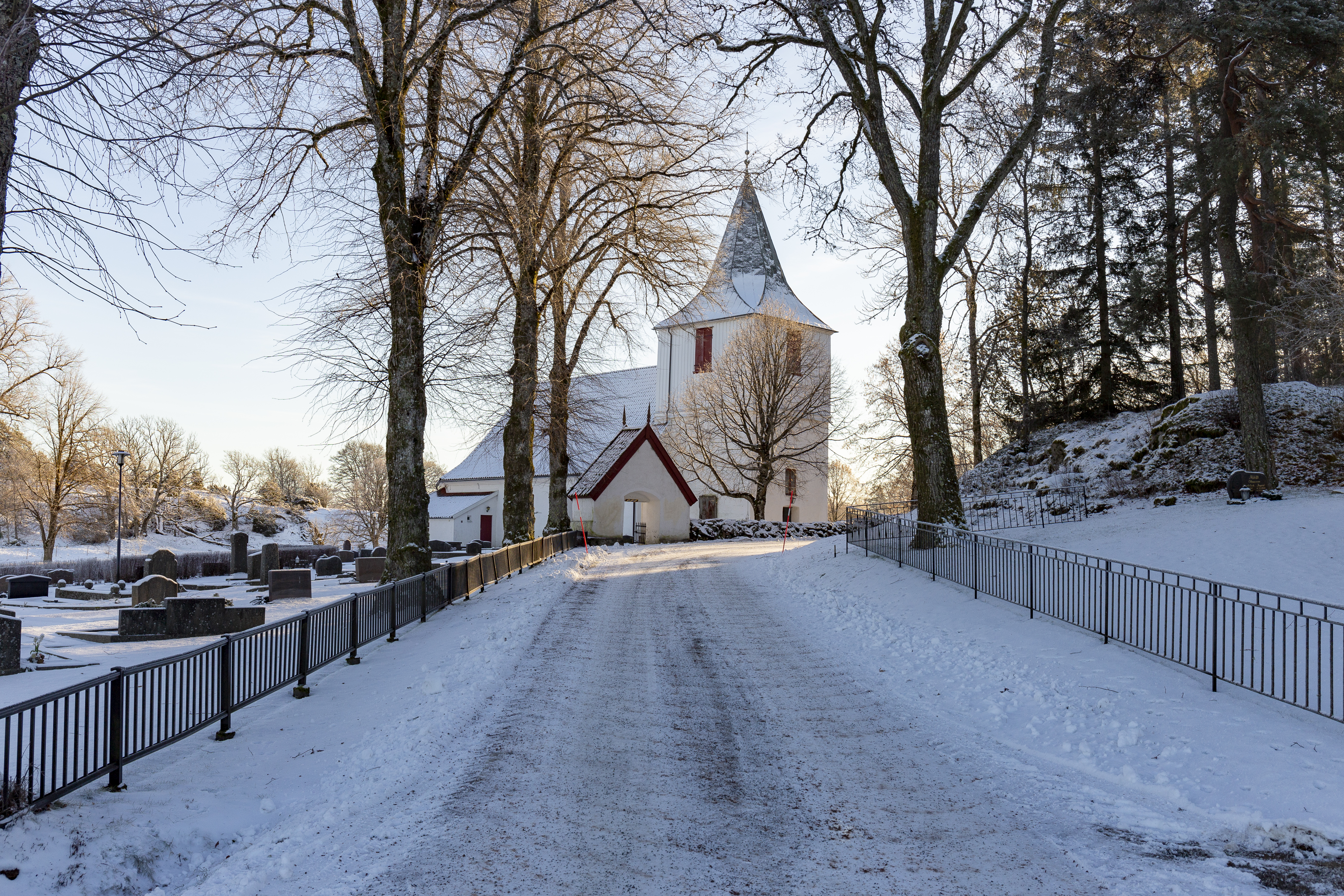 Vinterbild på en liten vit kyrka med ett kraftigt torn.