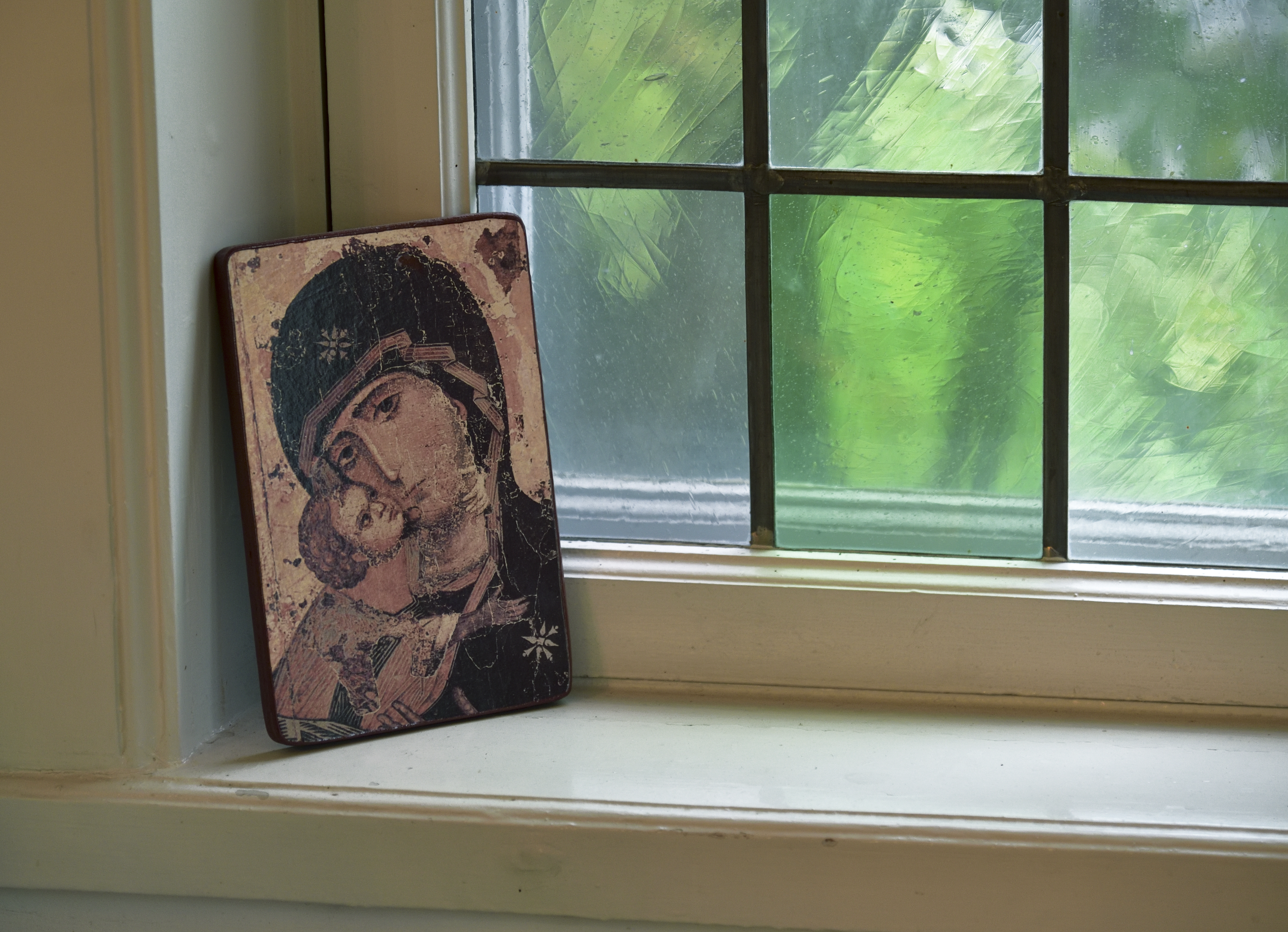 En ikonbild som föreställer en kvinna med ett barn står intill ett kyrkfönster.