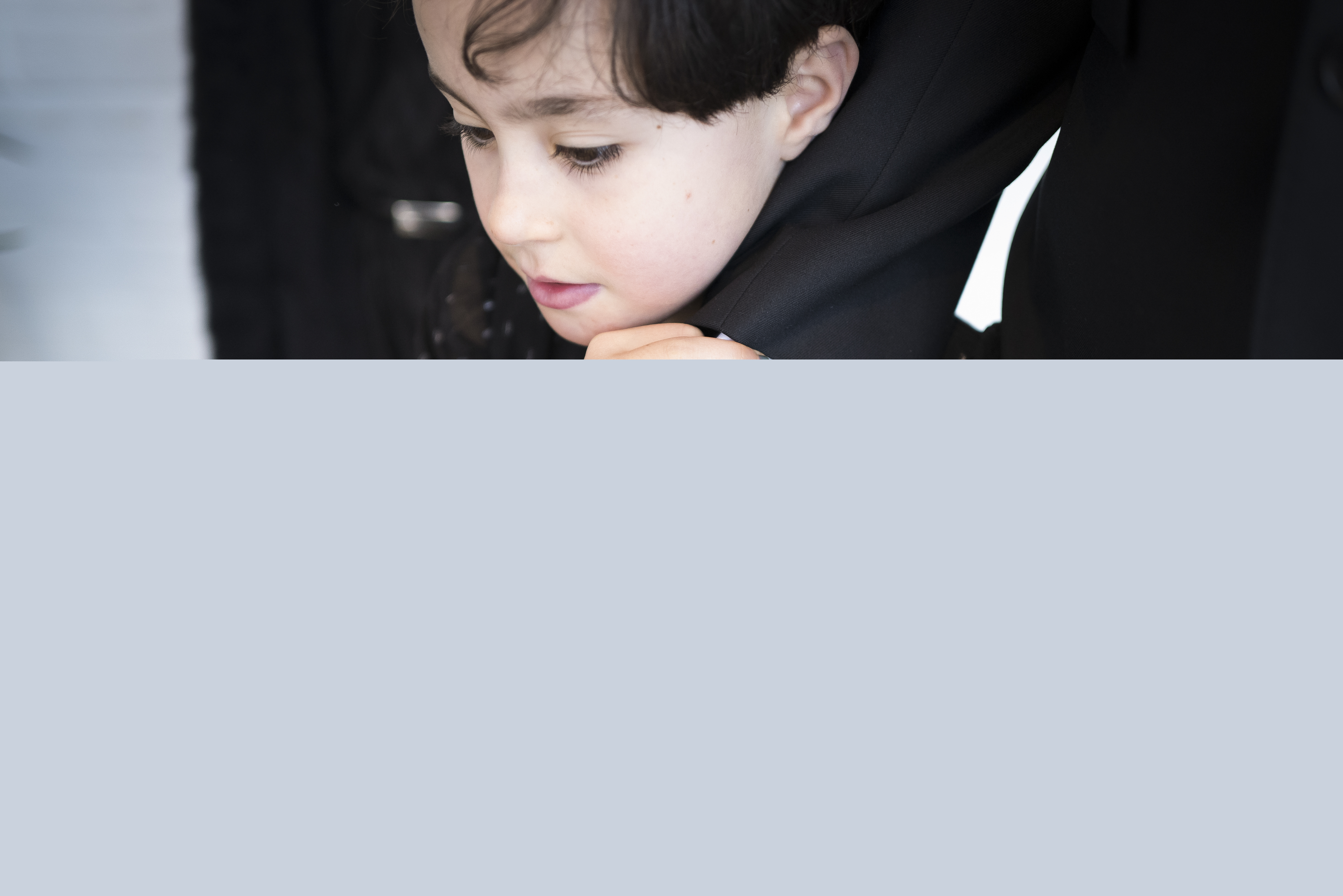 Ett barn håller en vuxens hand med båda händerna.