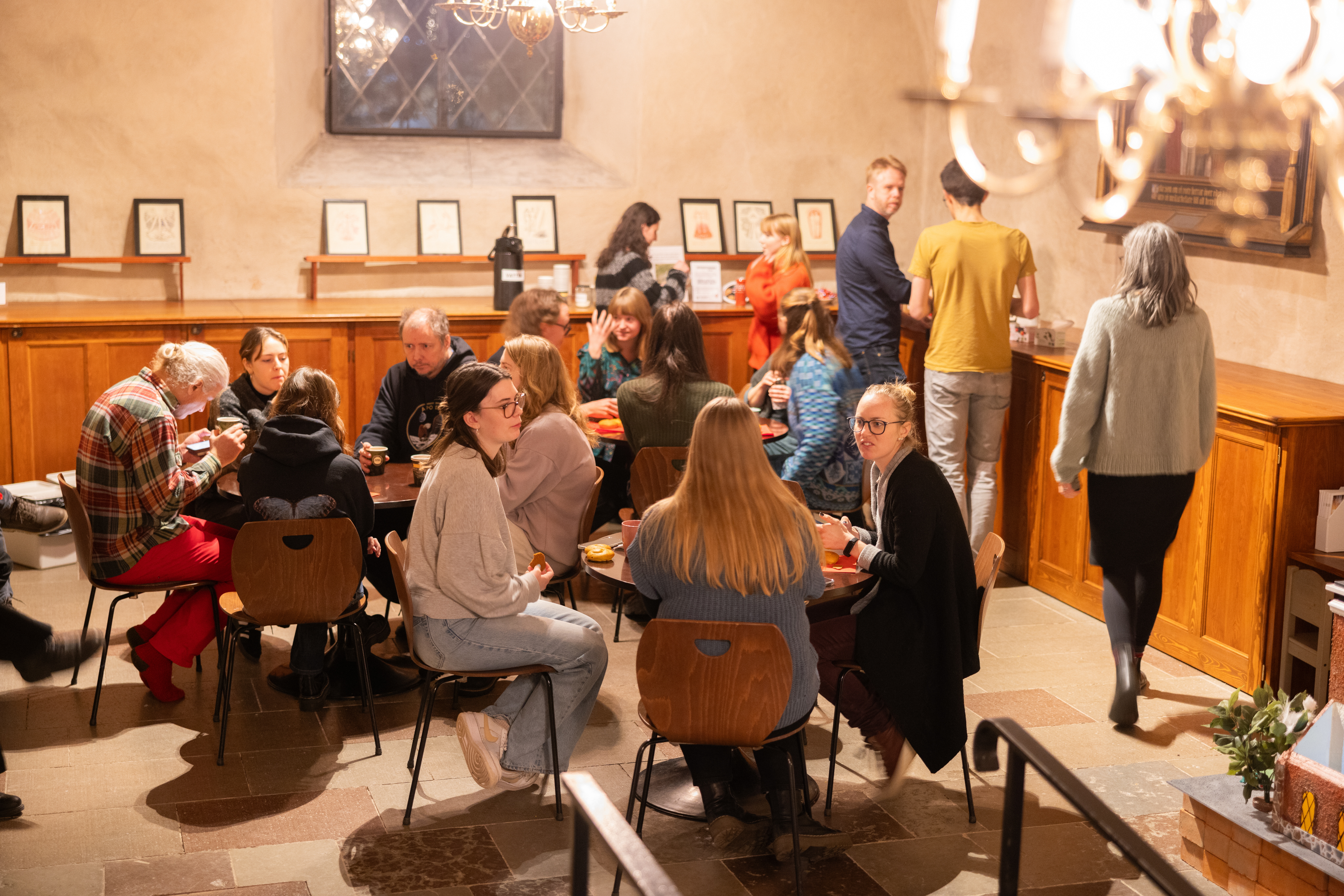 Ett tjugotal unga vuxna sitter och fikar i en kyrka.