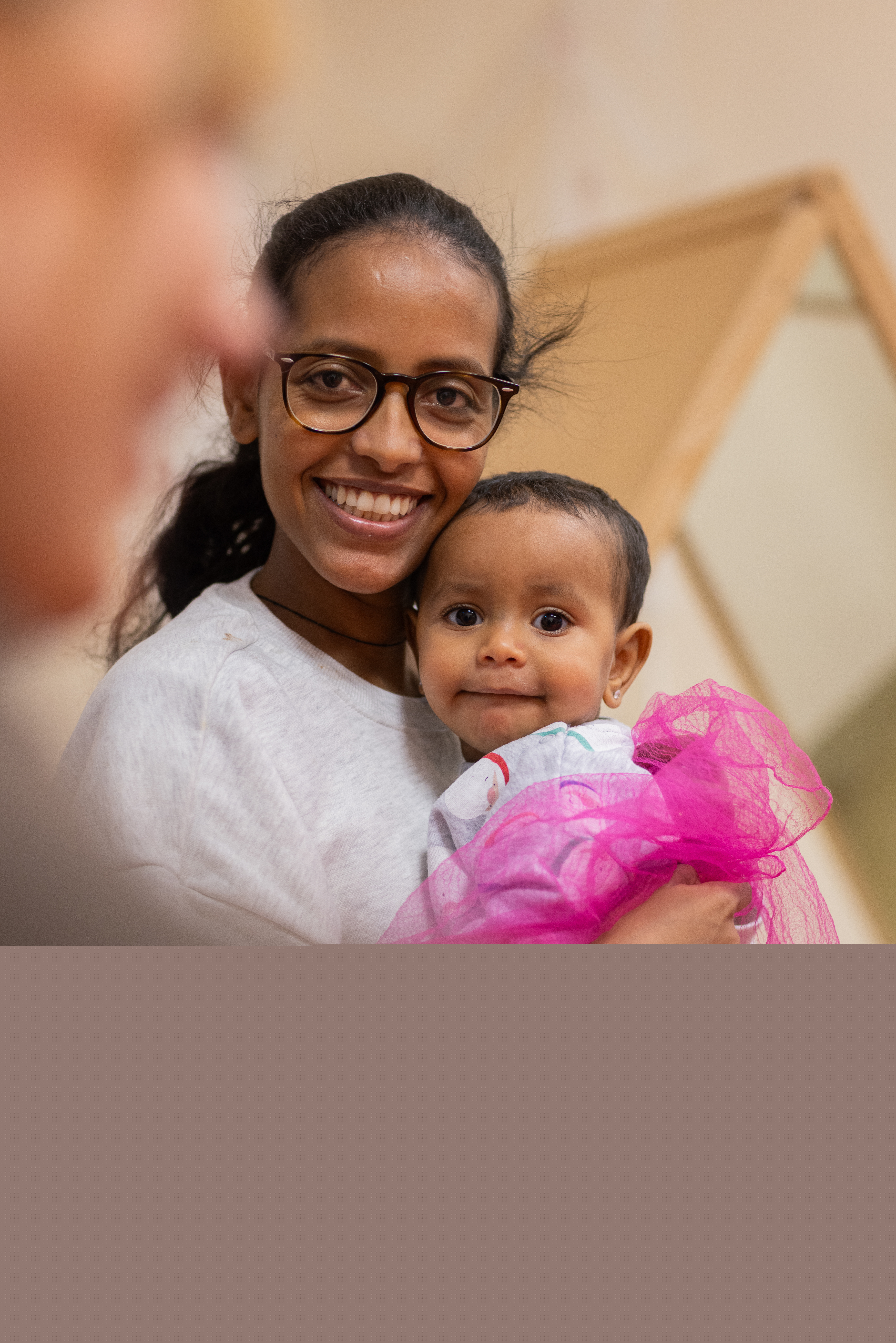 En mamma sitter med en bebis i famnen.