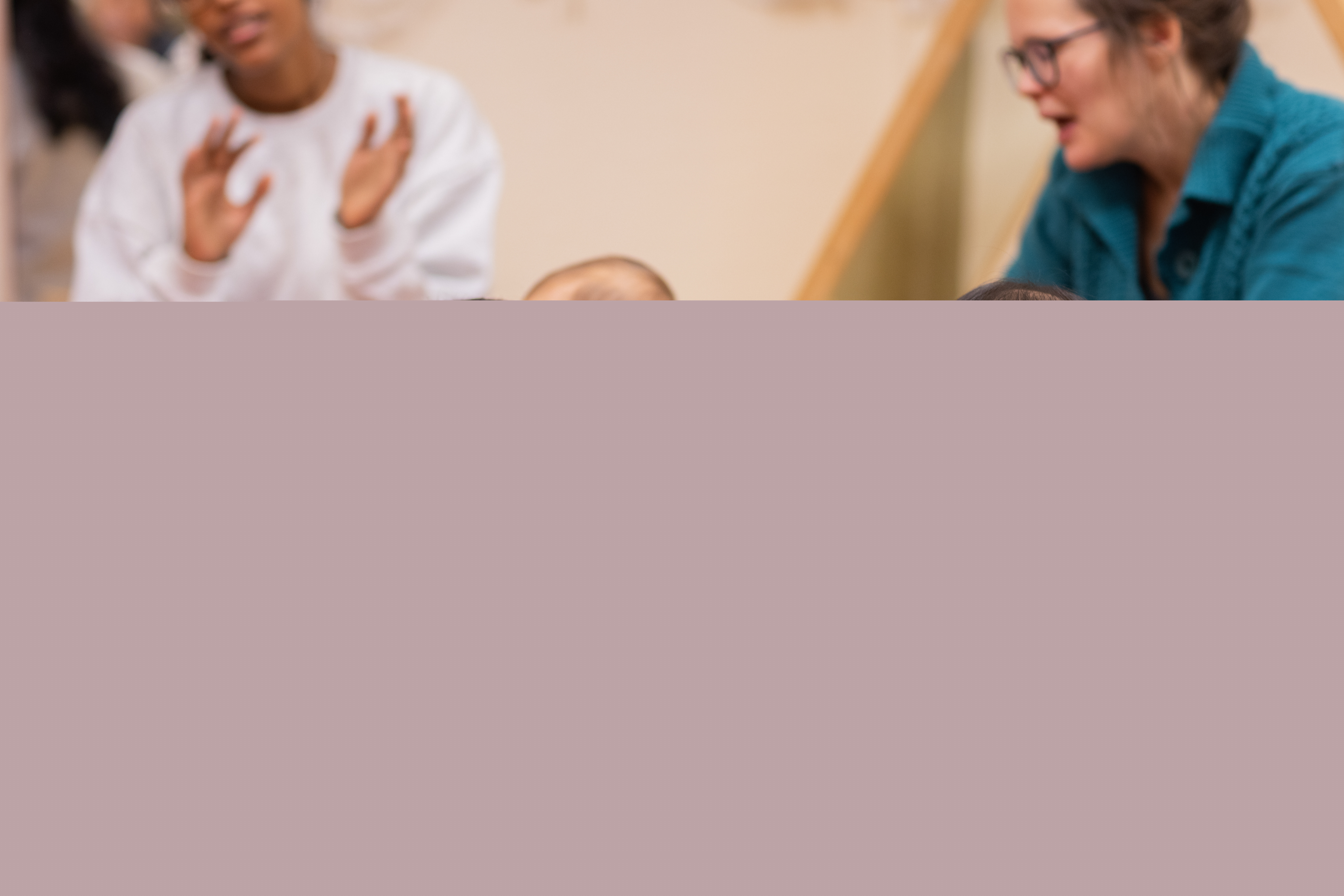 Tre bebisar sitter på en matta. Deras föräldrar sitter runt om.