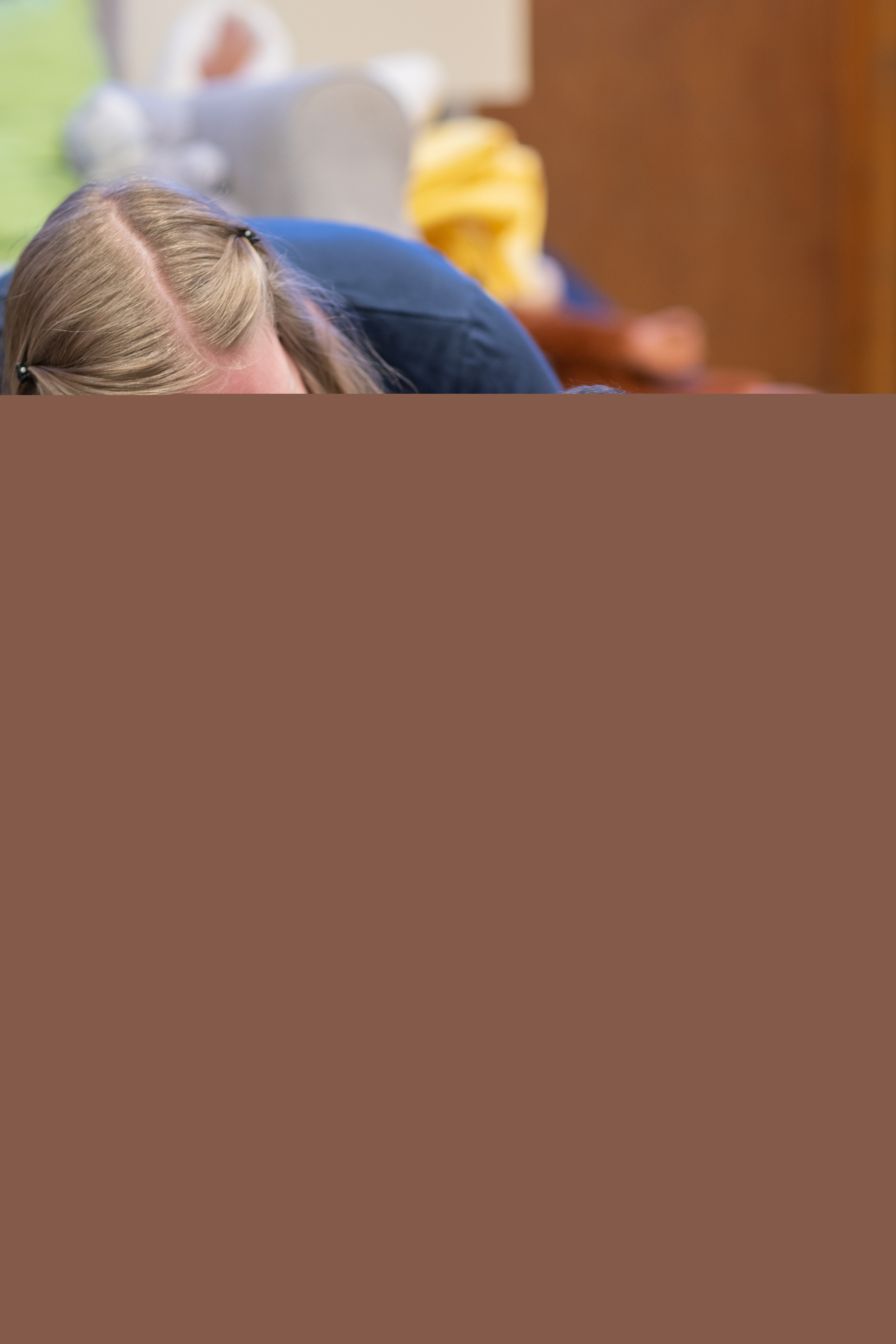 Två bebisar och en mamma skrattar på golvet.