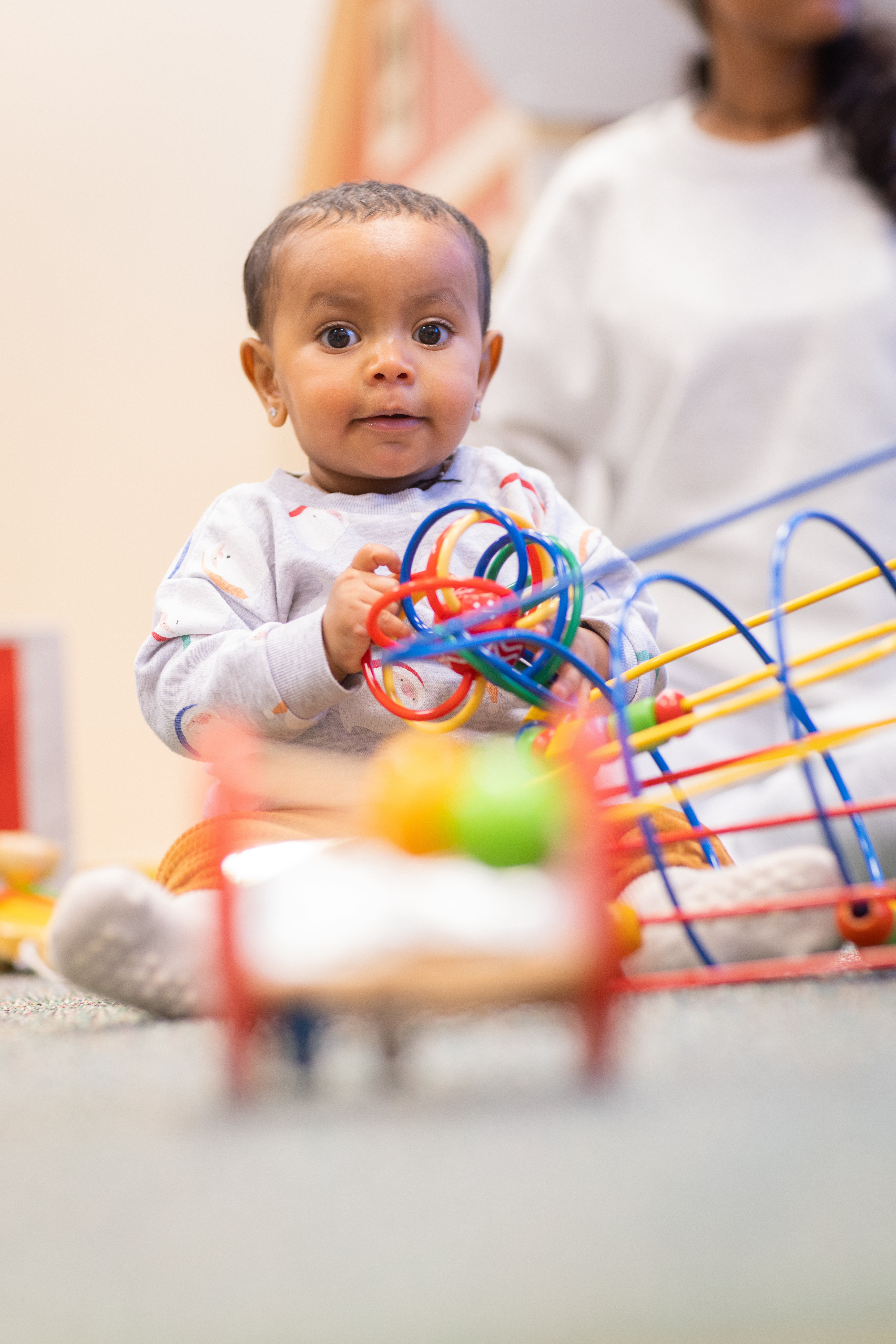 En bebis sitter på golvet och leker.
