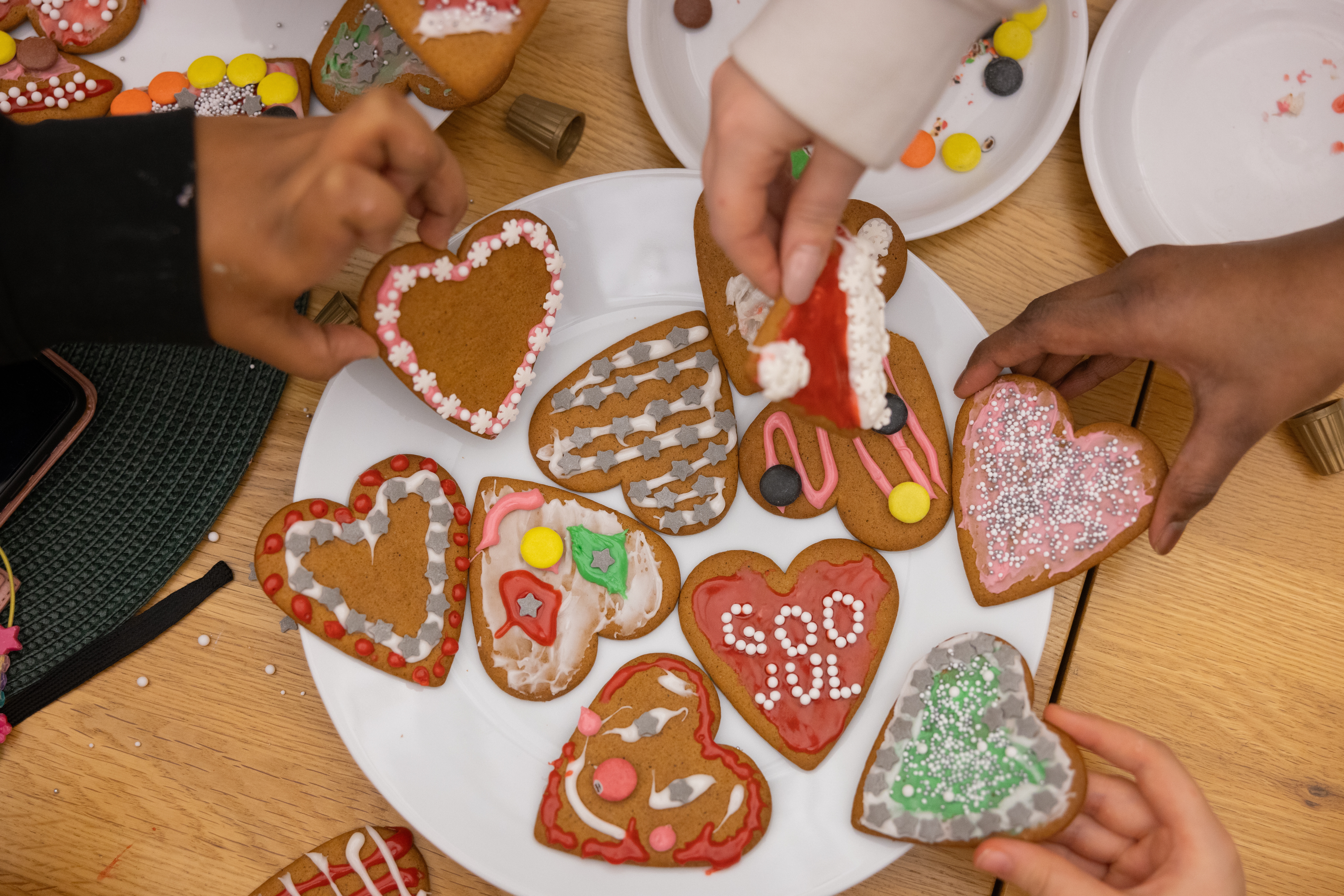 En tallrik med garnerade pepparkakshjärtan och barnhänder som lägger dit dem.
