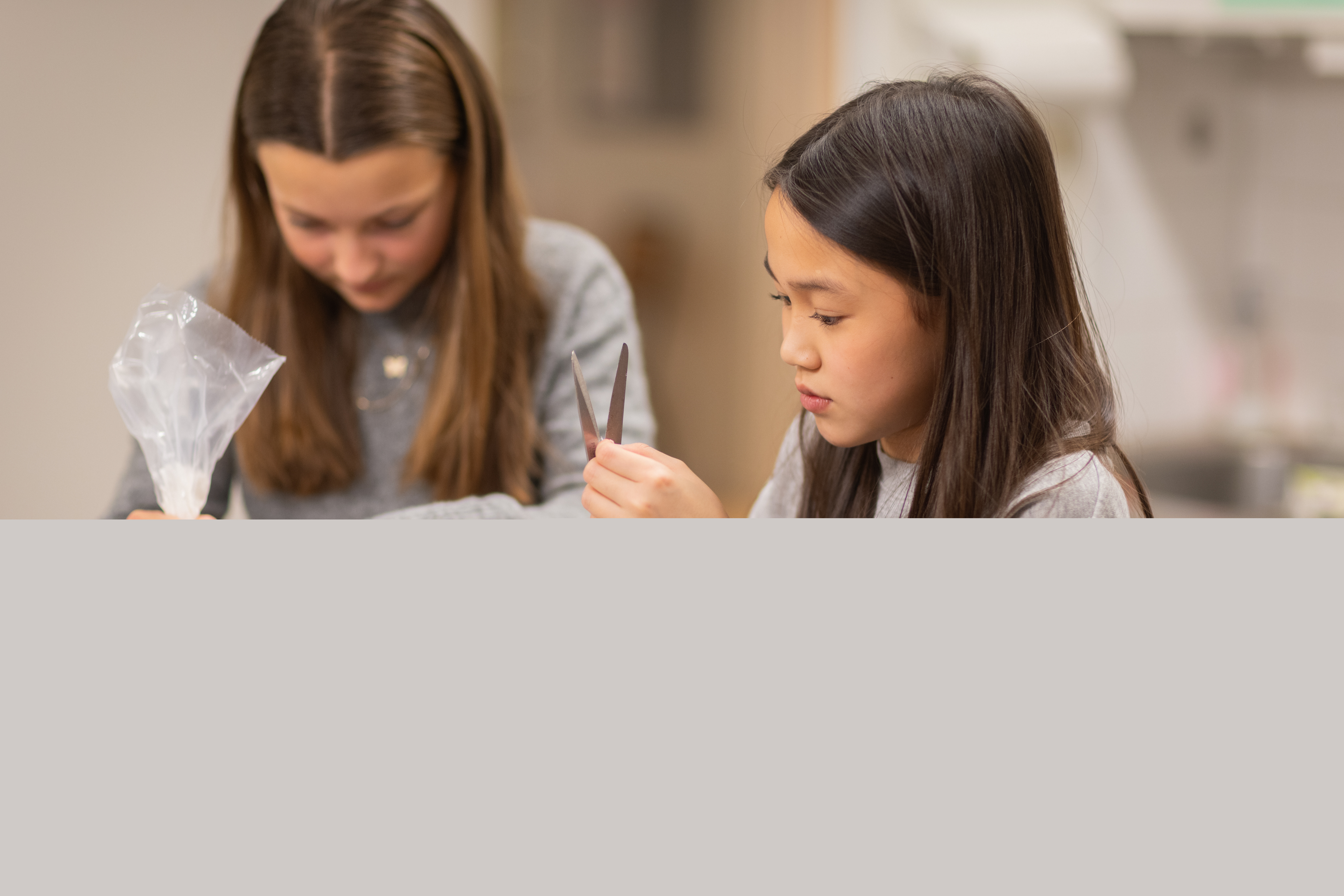 Två flickor pysslar i ett kök.