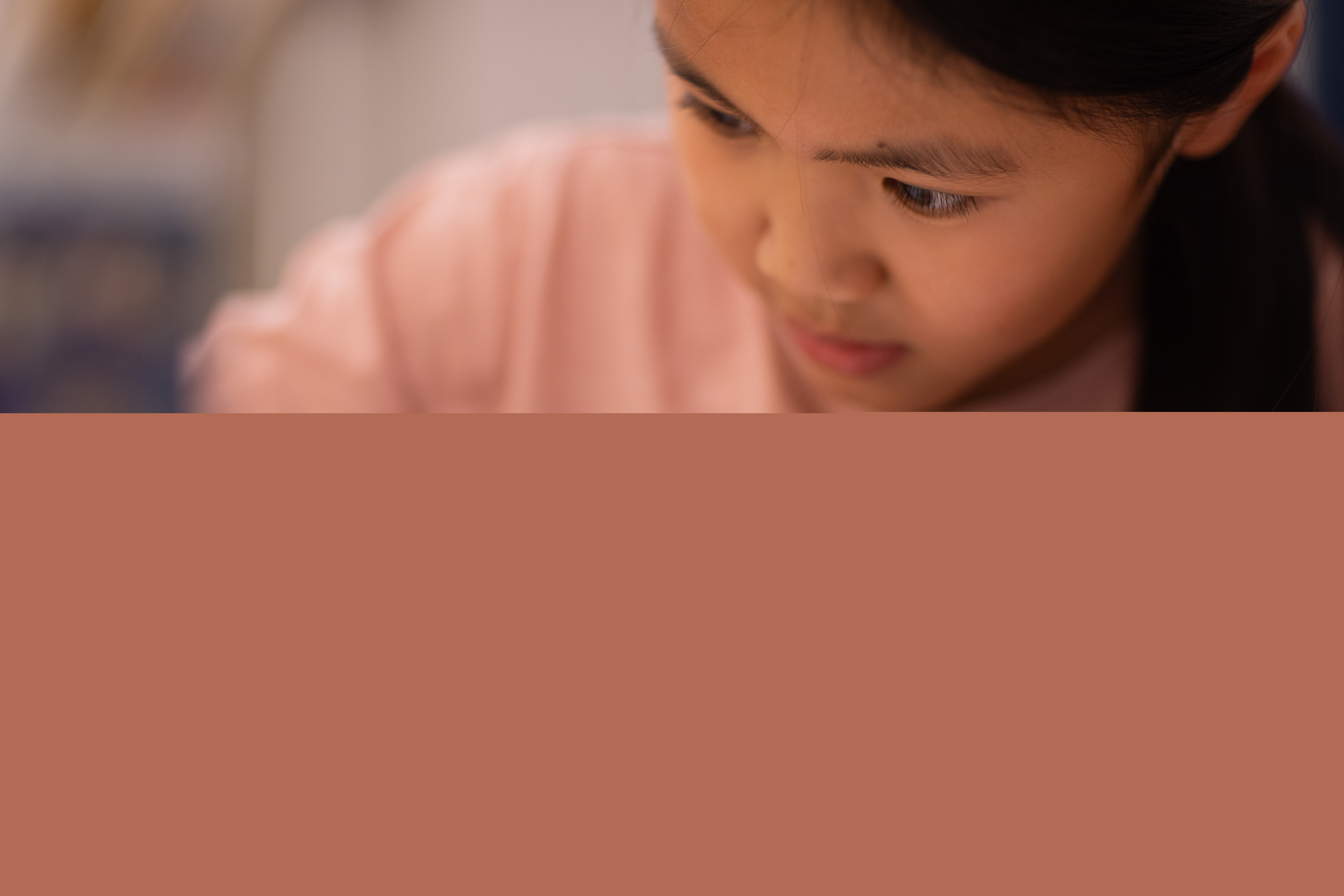 En liten flicka sitter och skriver vid ett bord.