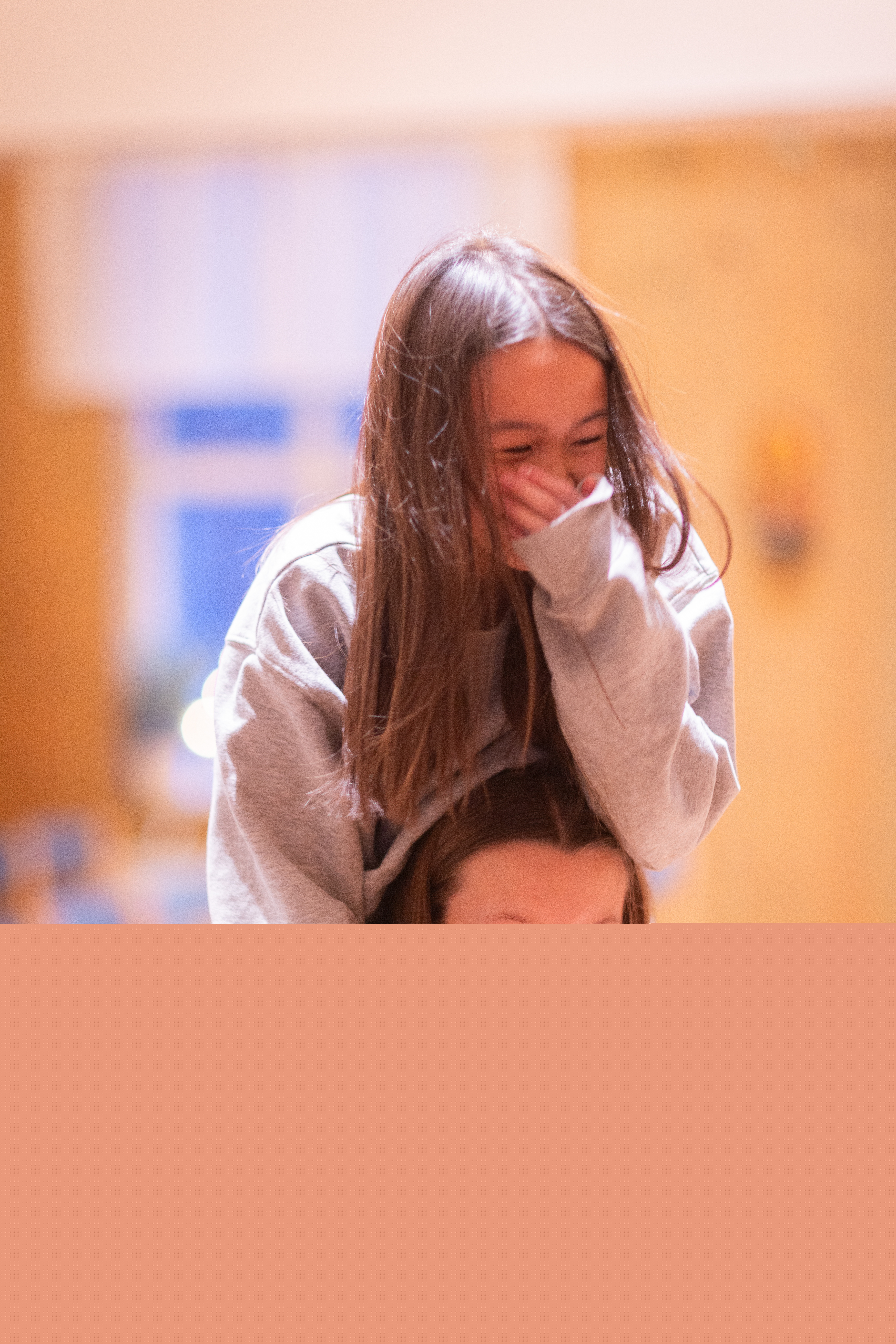 En tjej bär en annan på sina axlar. Båda skrattar.