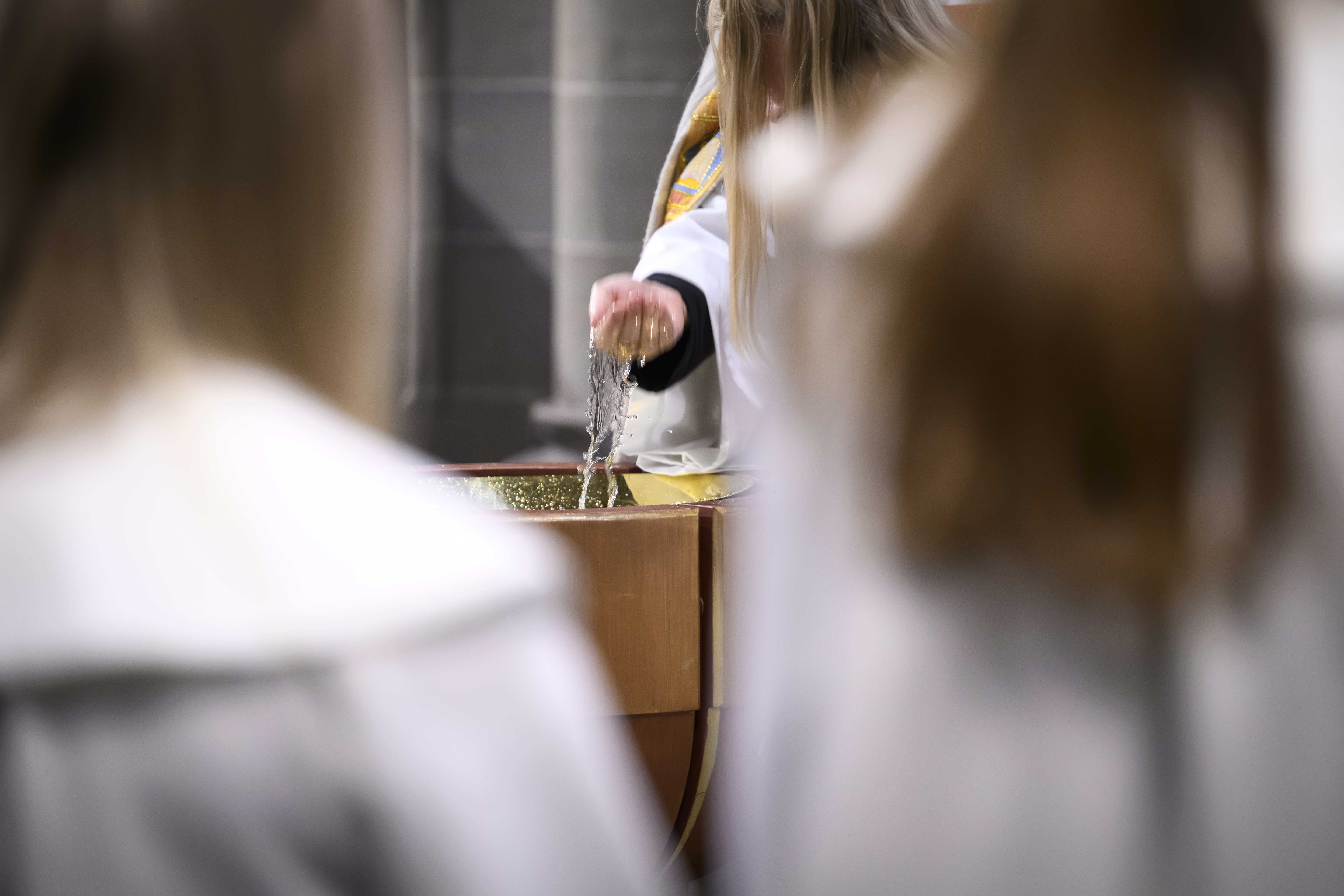 Prästen håller sin hand på en konfirmands huvud när hon döps. 