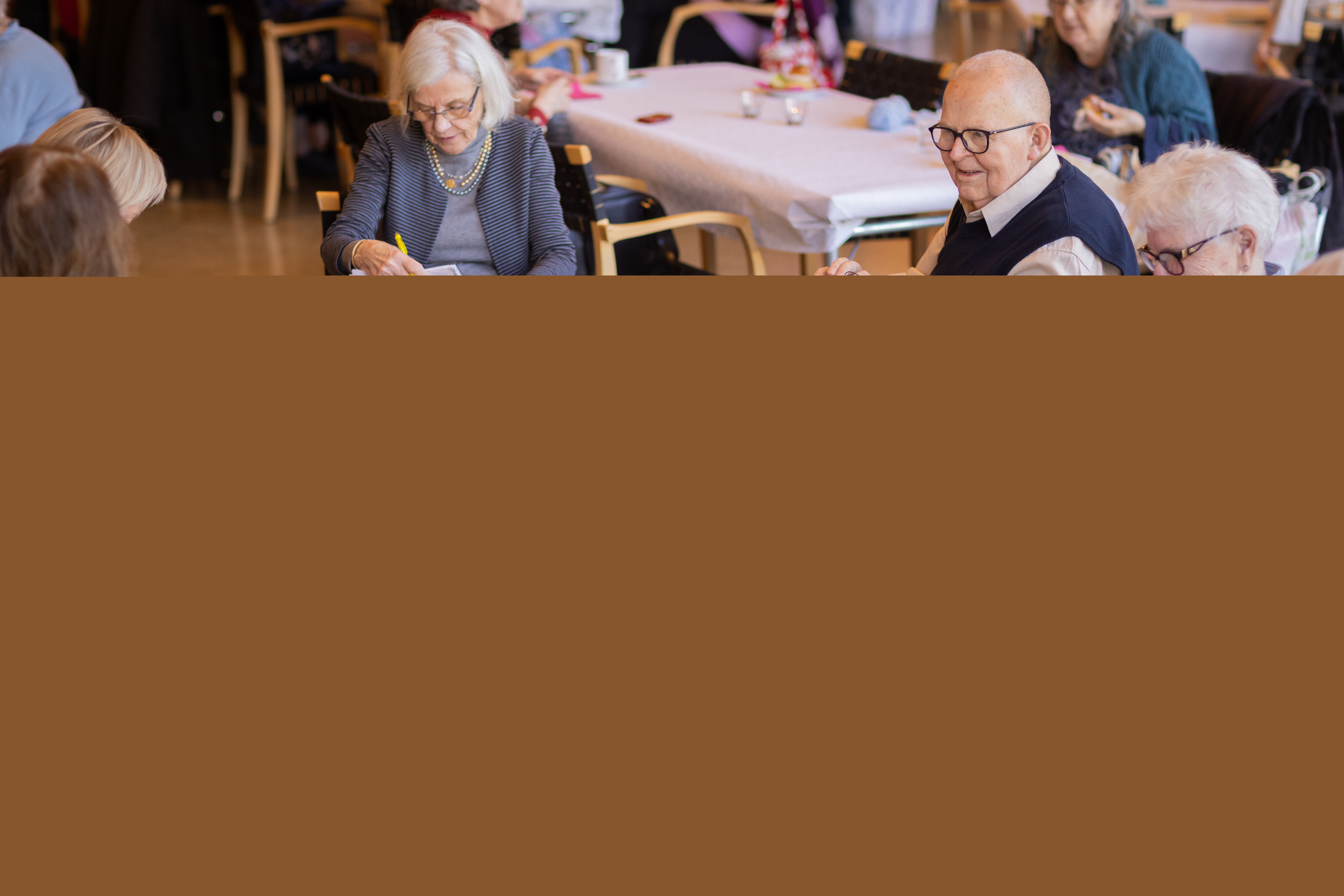 Flera äldre personer sitter vid ett bord och pysslar.