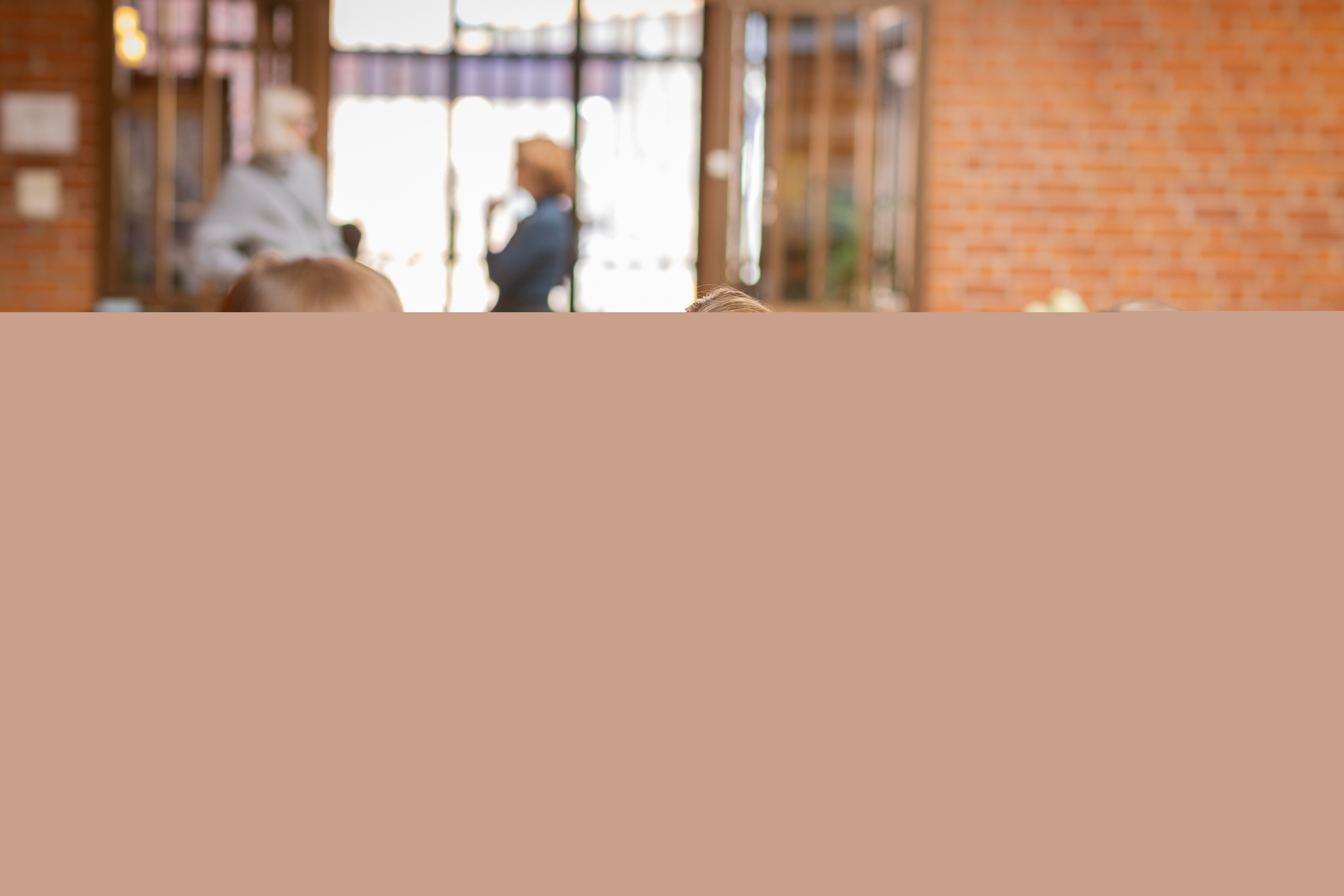 En kvinnlig präst sitter vid ett bord och samtalar med två andra personer.