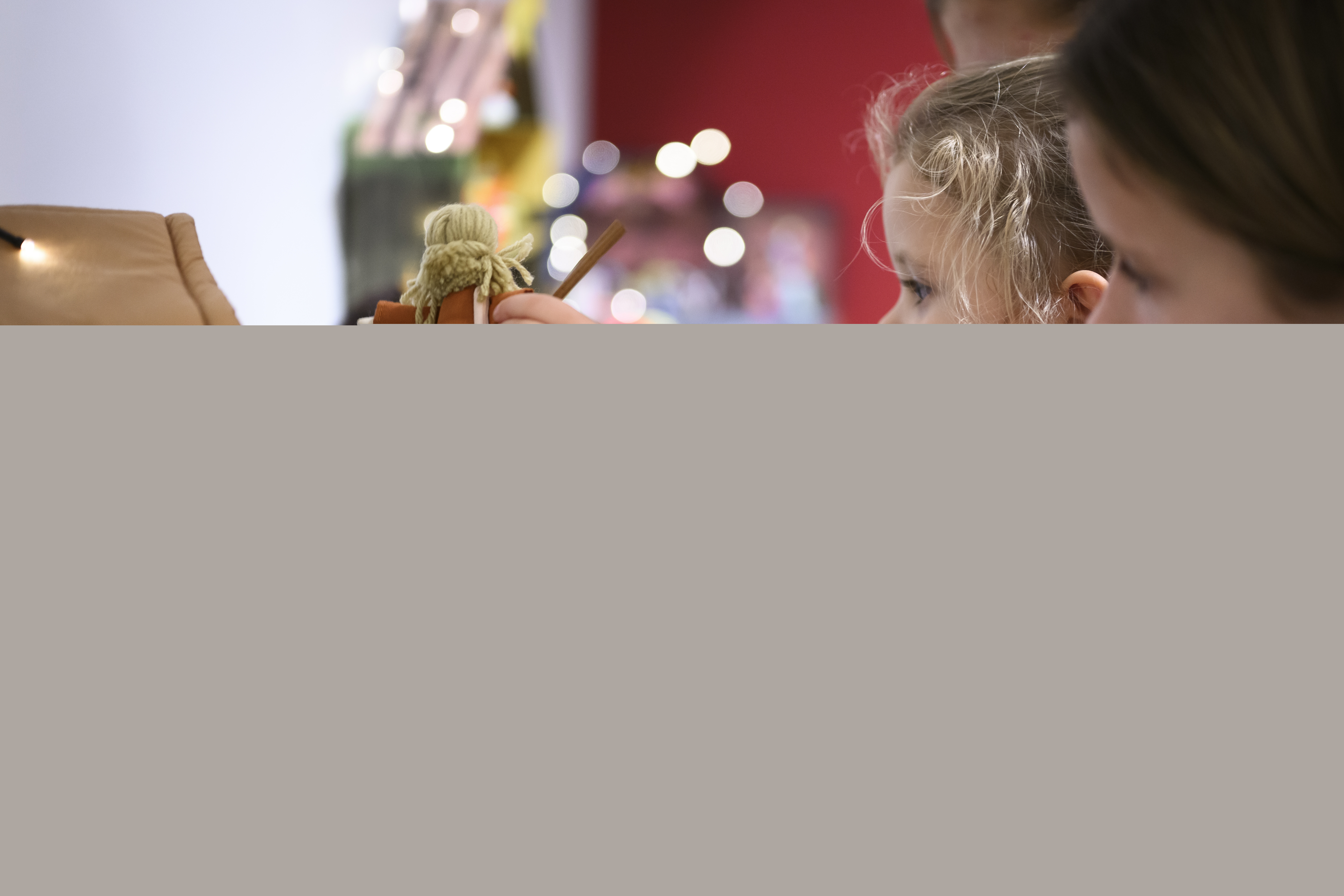 Ett litet barn i röd tröja leker med en julkrubba i mjukistyg.