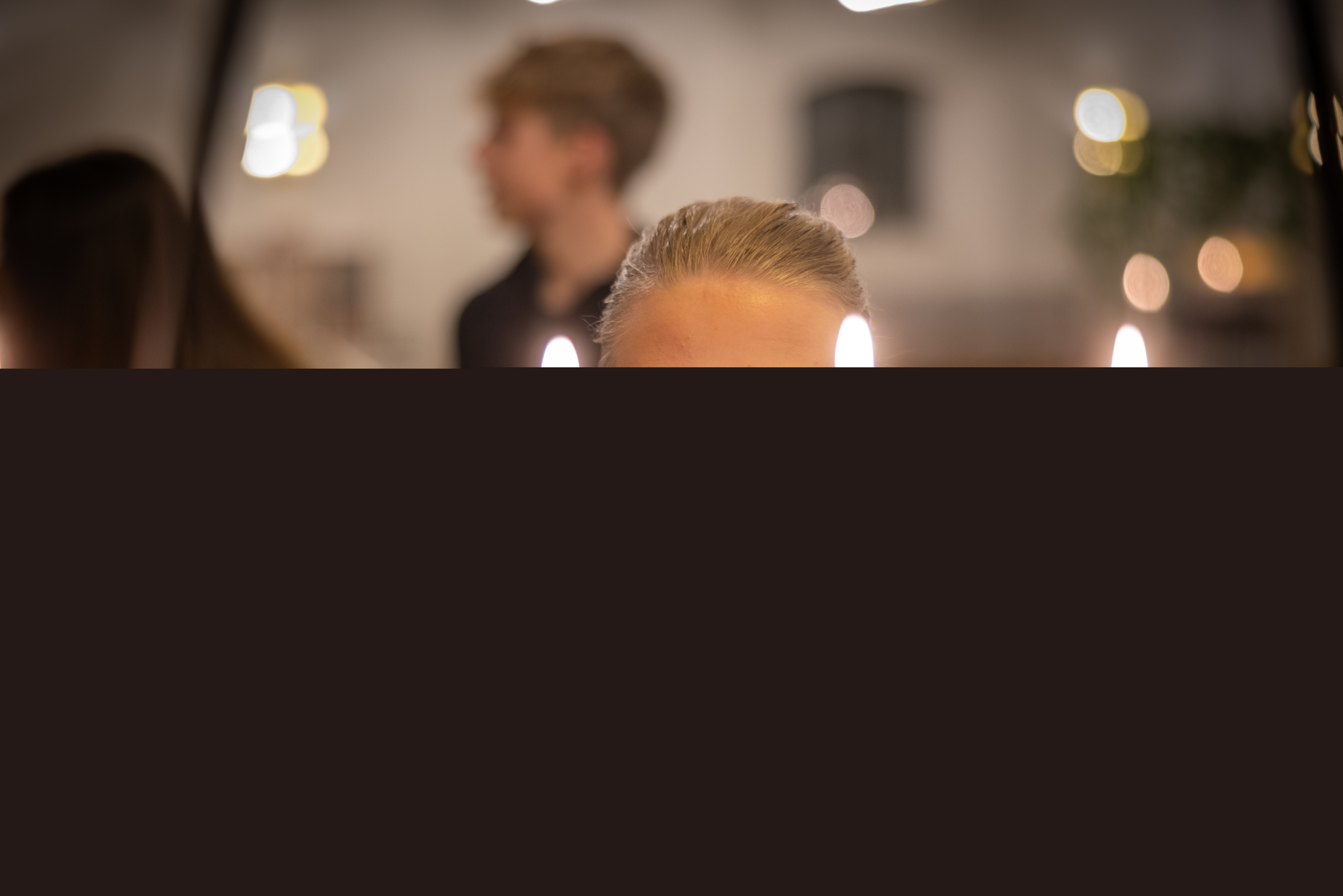 En tjej står framför en ljusbärare med tända ljus. I bakgrunden står några ungdomar.