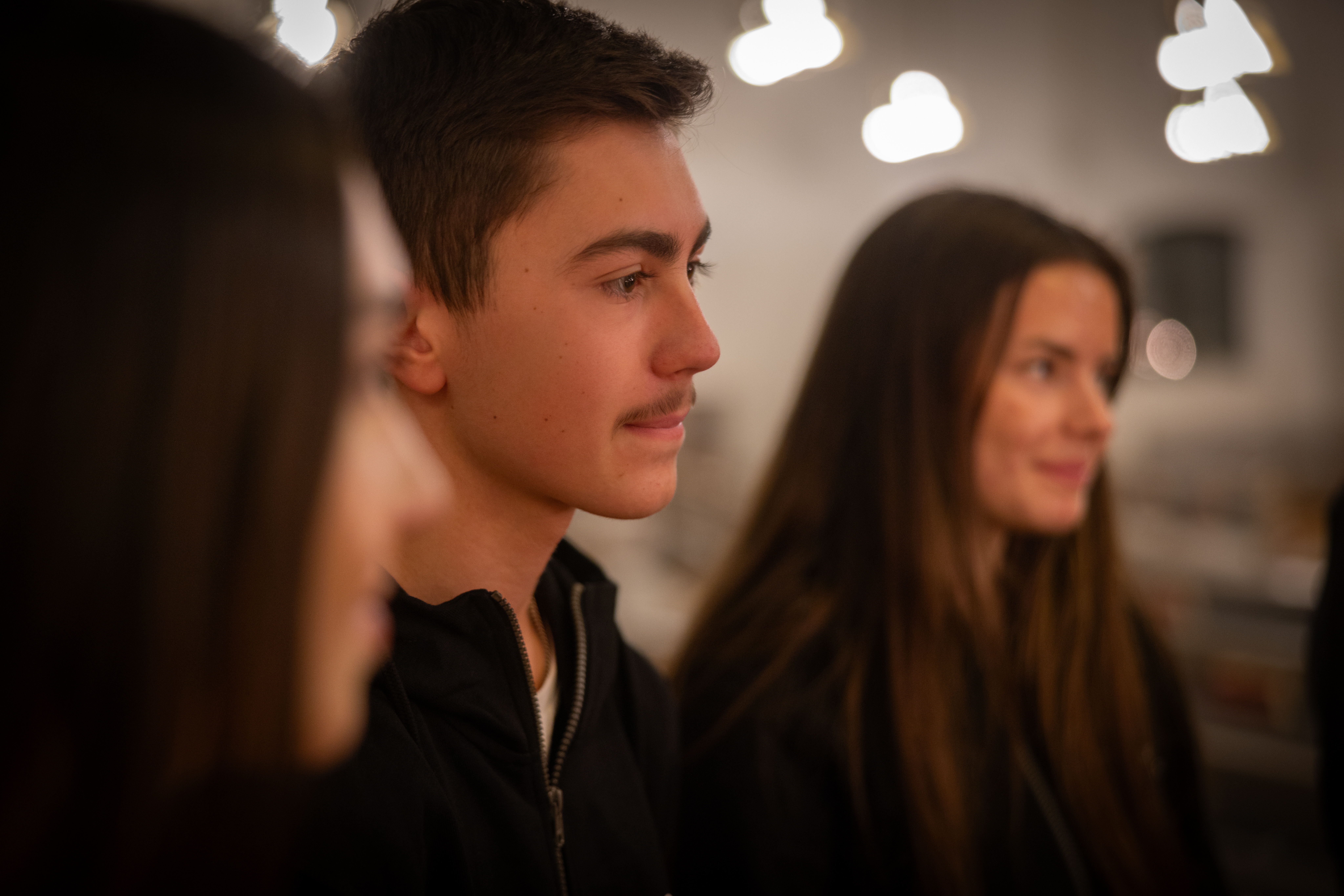 En närbild på tre ungdomar som sitter bredvid varandra.