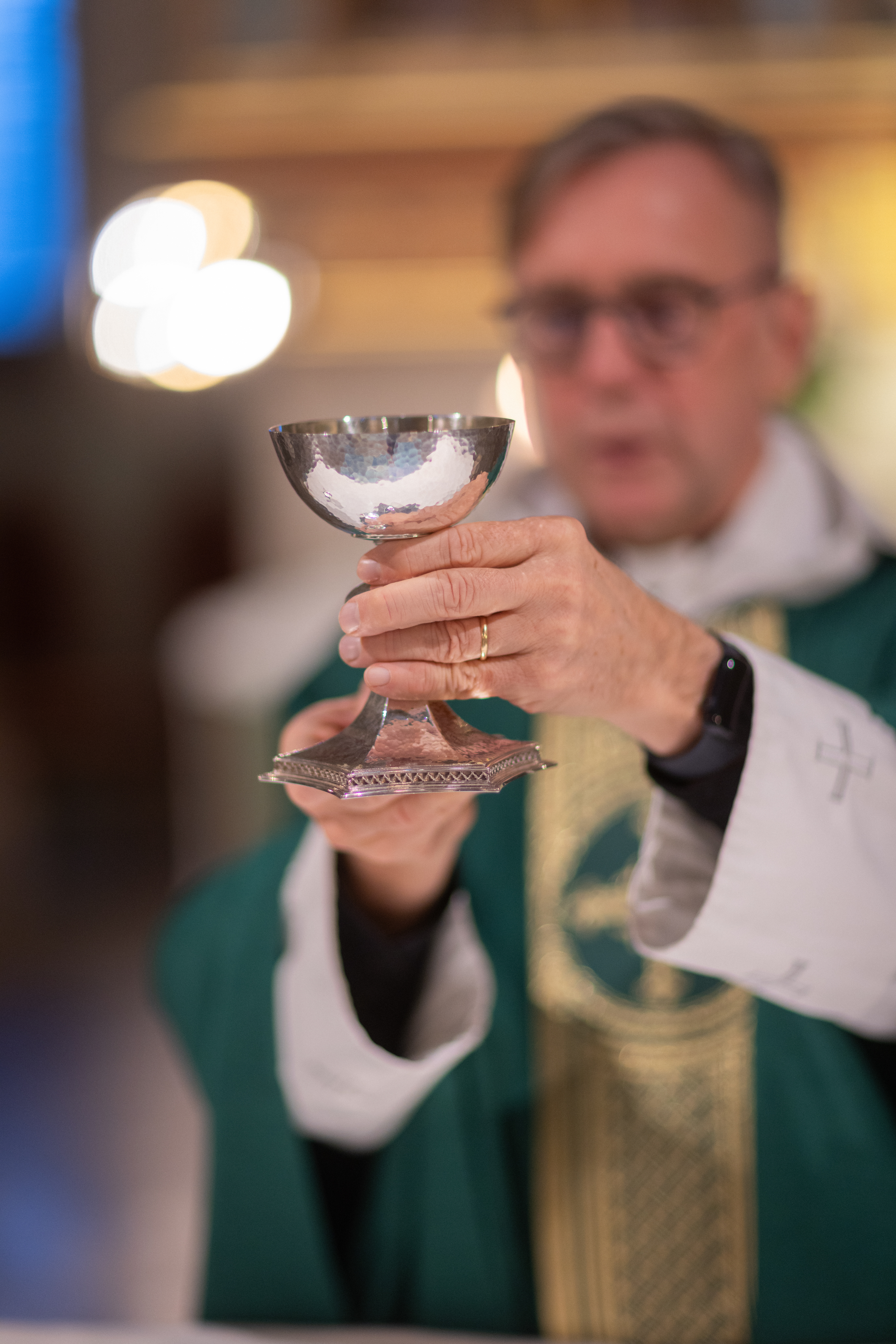 En präst lyfter upp nattvardskalken.