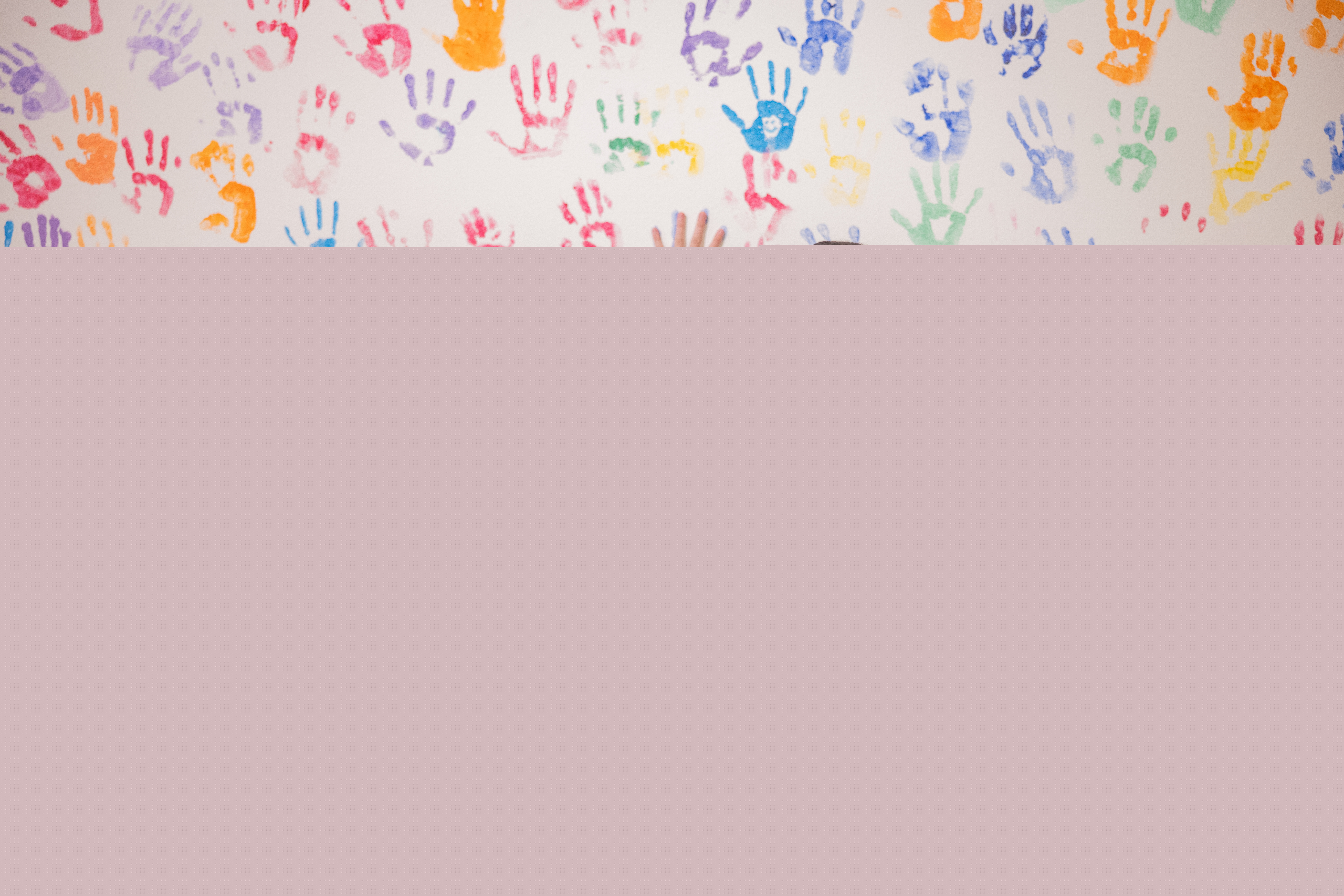 Fyra tjejer har färgat sina händer letar nu tomma ytor på en vägg full av färgglada handavtryck.