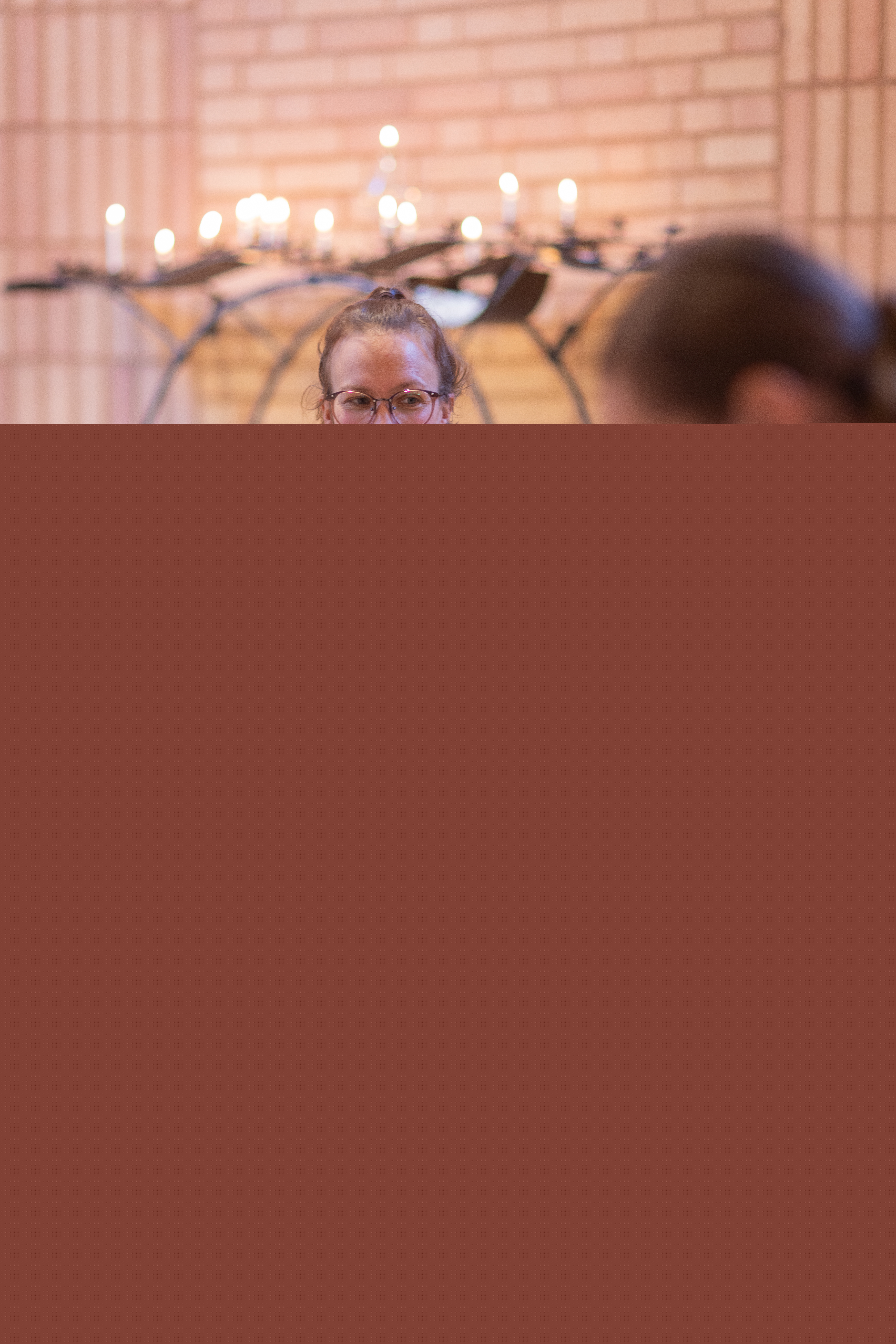 Två kvinnor sitter på golvet och leker med barnen på en öppen förskola. Tända ljus i bakgrunden.