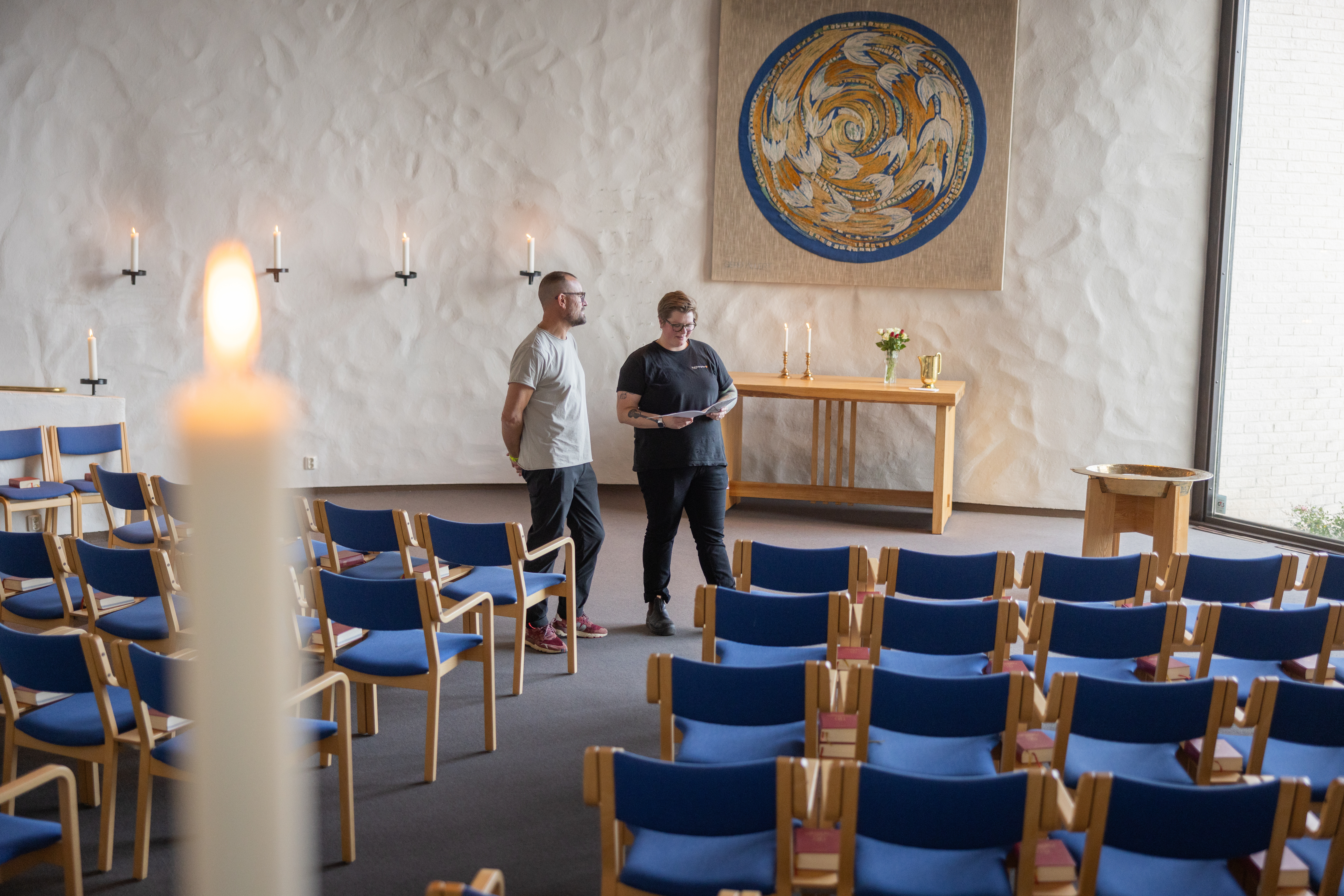 Två personer samtalar framför ett altare.