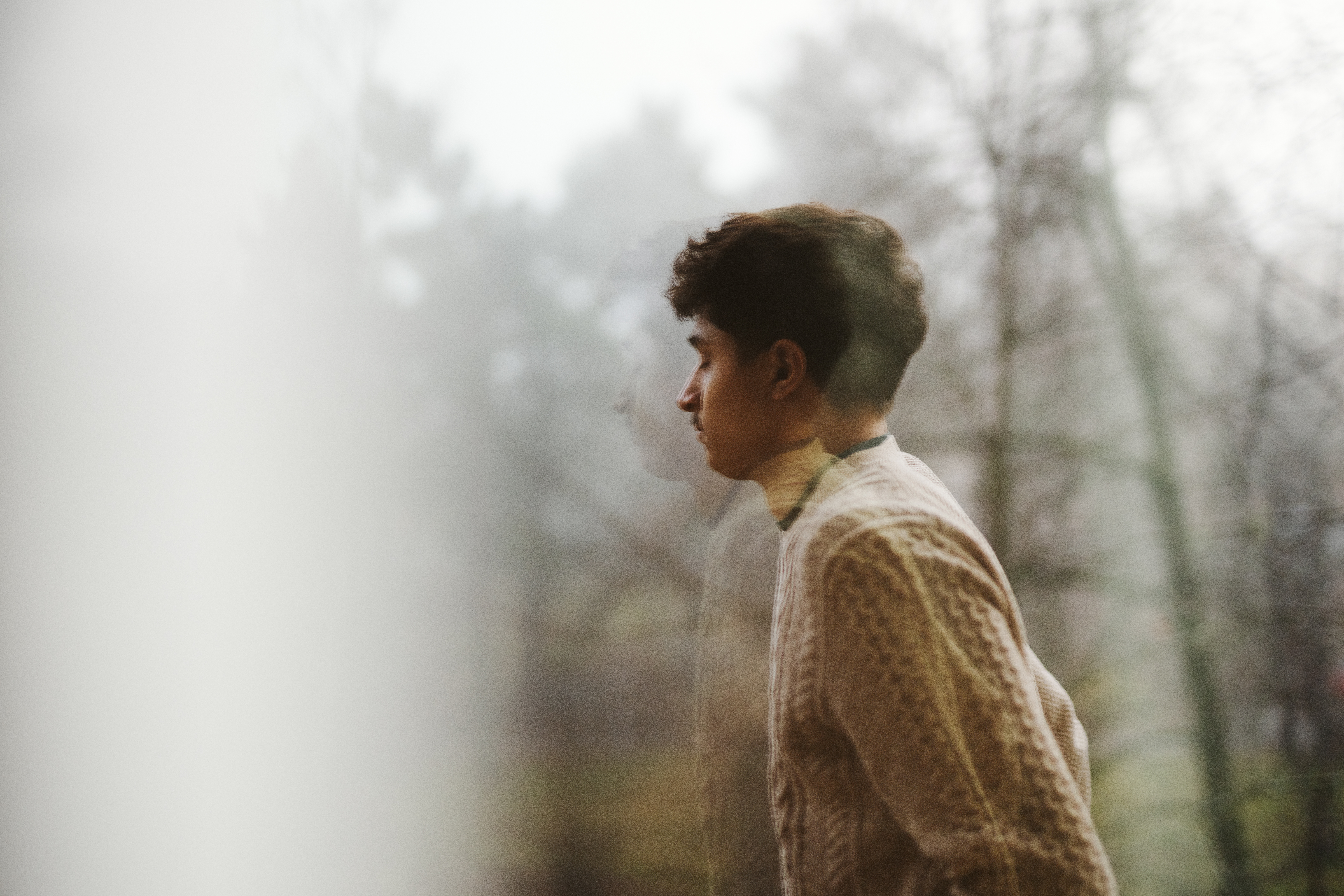 En ung man utomhus. Träd och dimma i omgivningen.